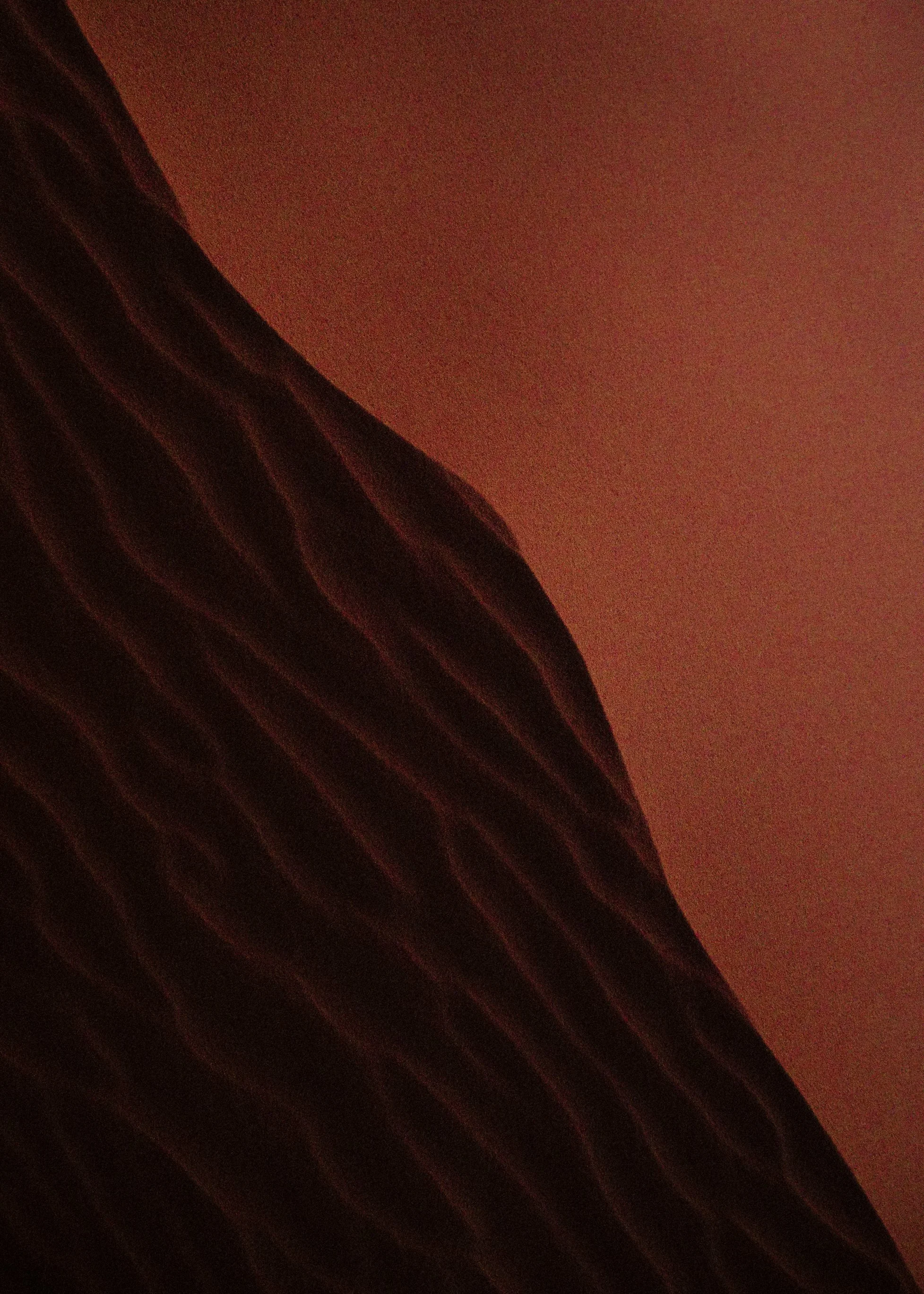 Fotografía de textura de dunas de arena roja con sombras profundas.