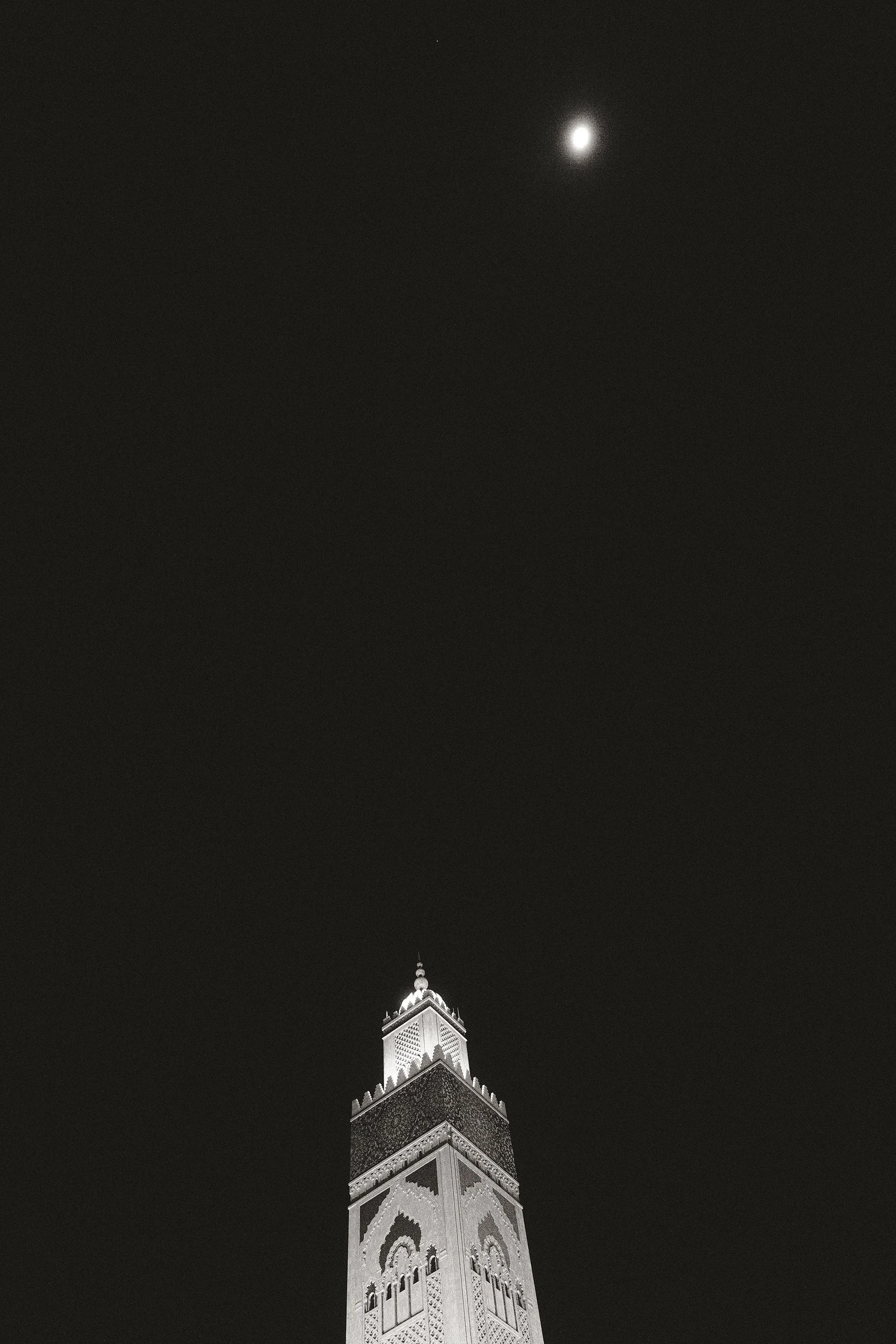 Fine art night photograph showing the architecture of an illuminated mosque contrasting against a dark sky under the moonlight.