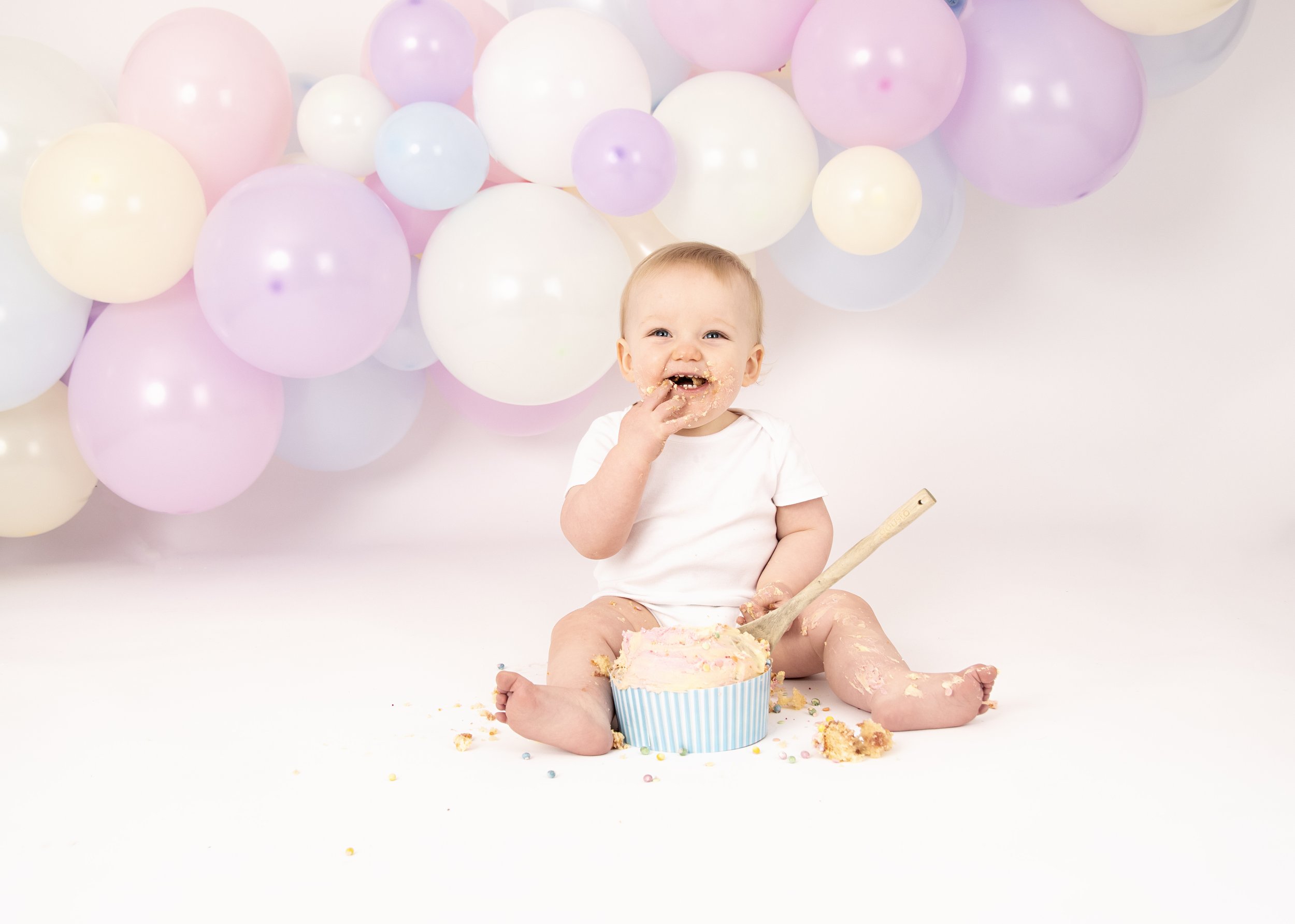 Baby with birthday cake and balloons