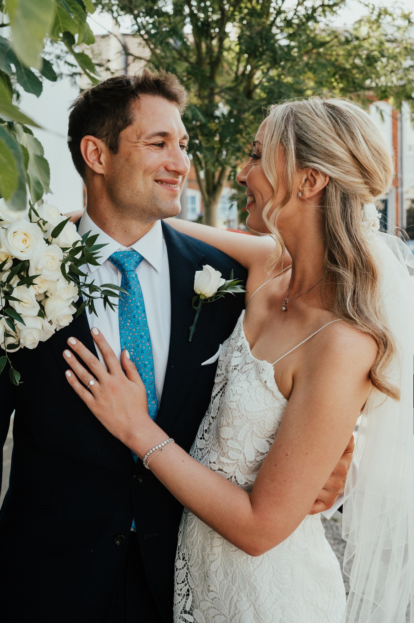 A bride and groom look at each other lovingly during their wedding, with greenery in the background.