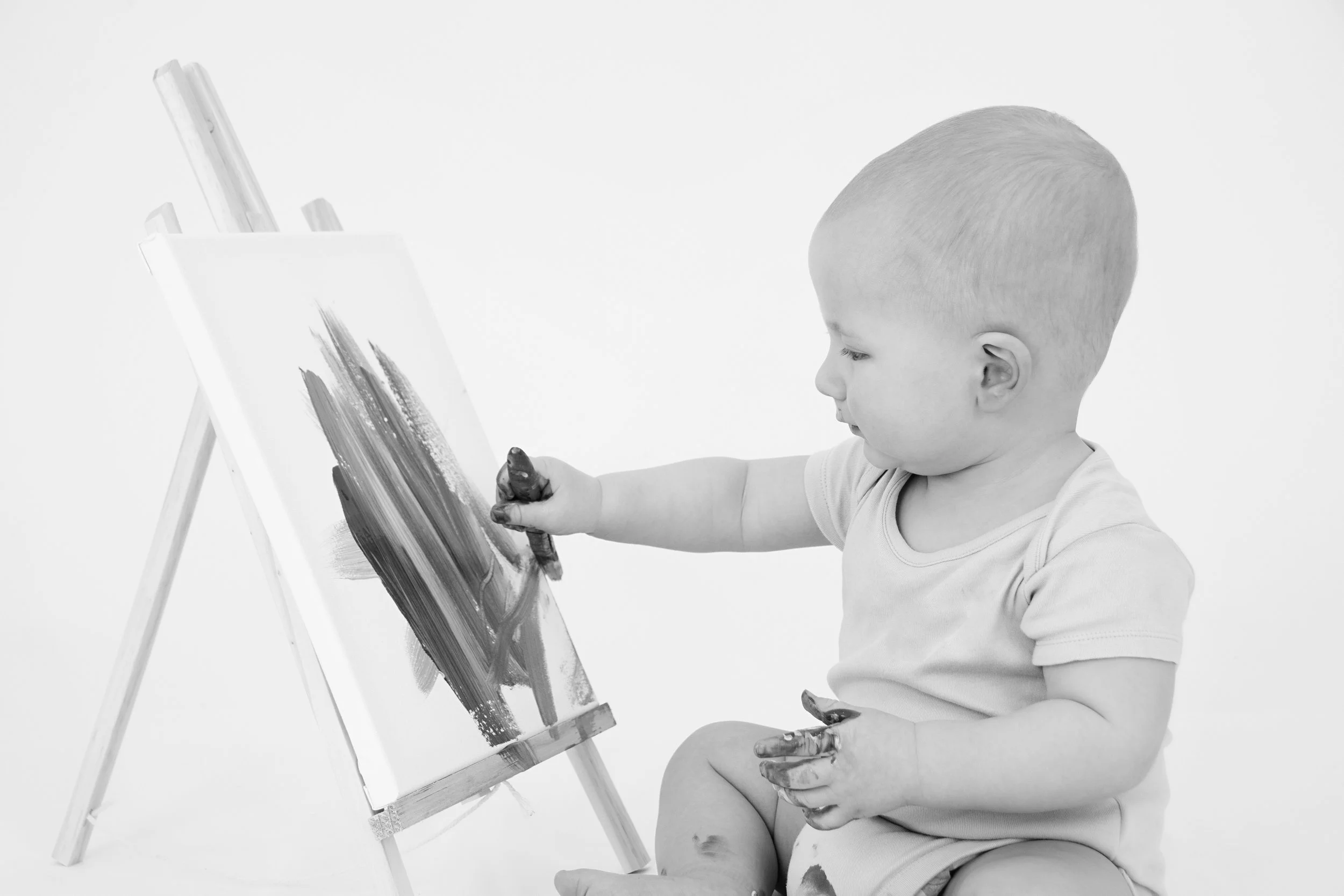 Baby painting with fingers on canvas, black and white