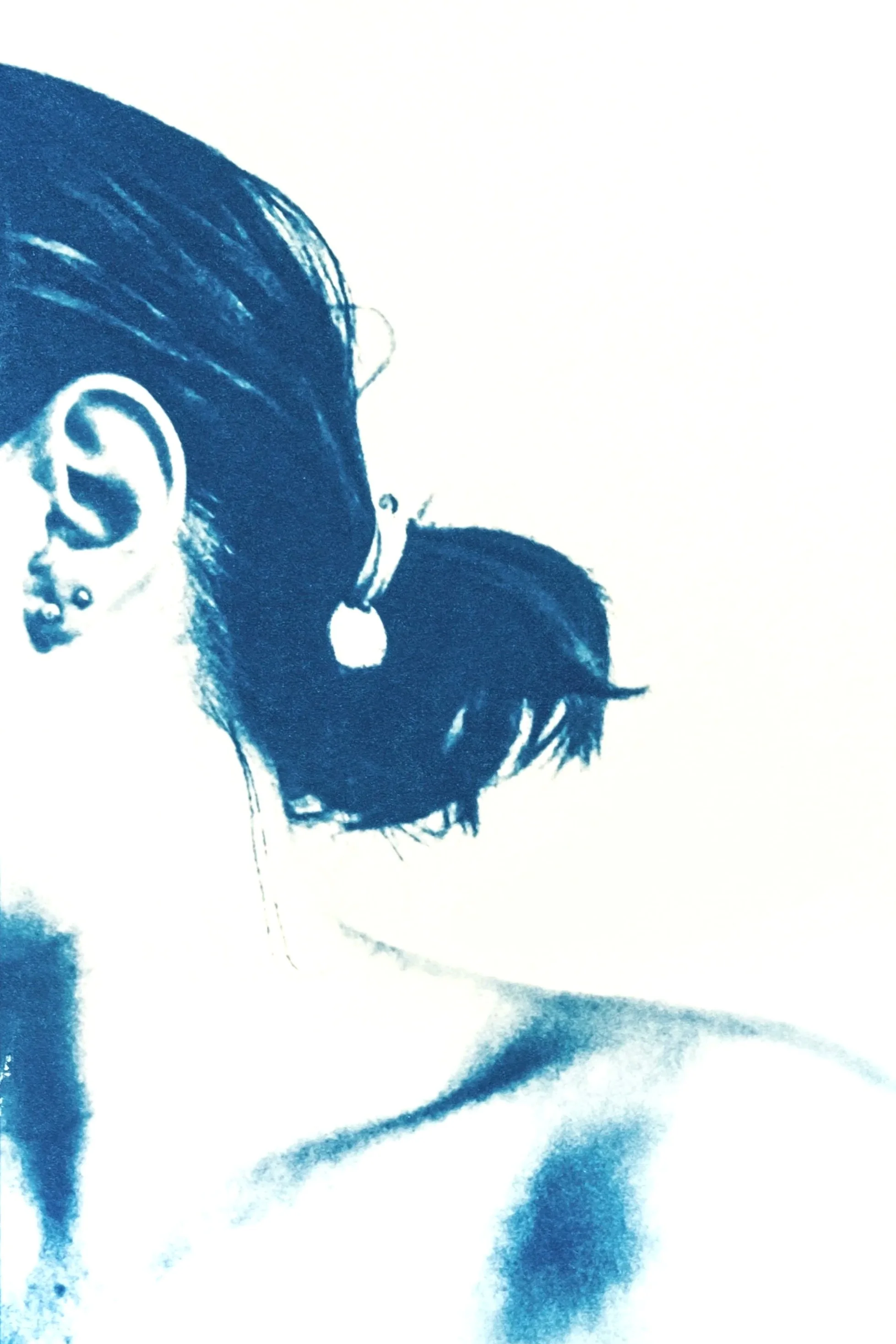 Close-up of a person's head and shoulder with dark hair and earring in a blue-tinted cyanotype photo