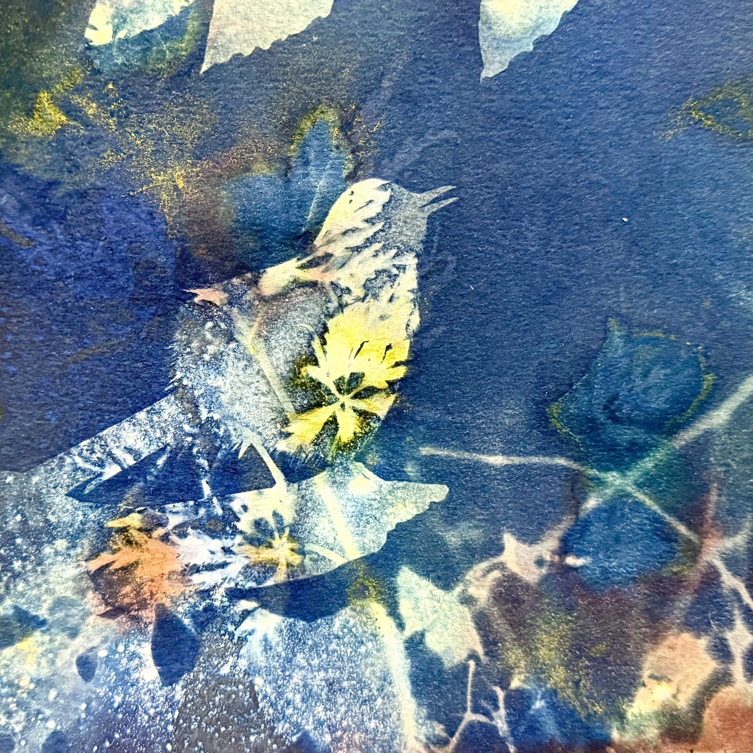 Double-exposure cyanotype with colorful background of yellow, green, and orange flowers and a bird, textured and vibrant.