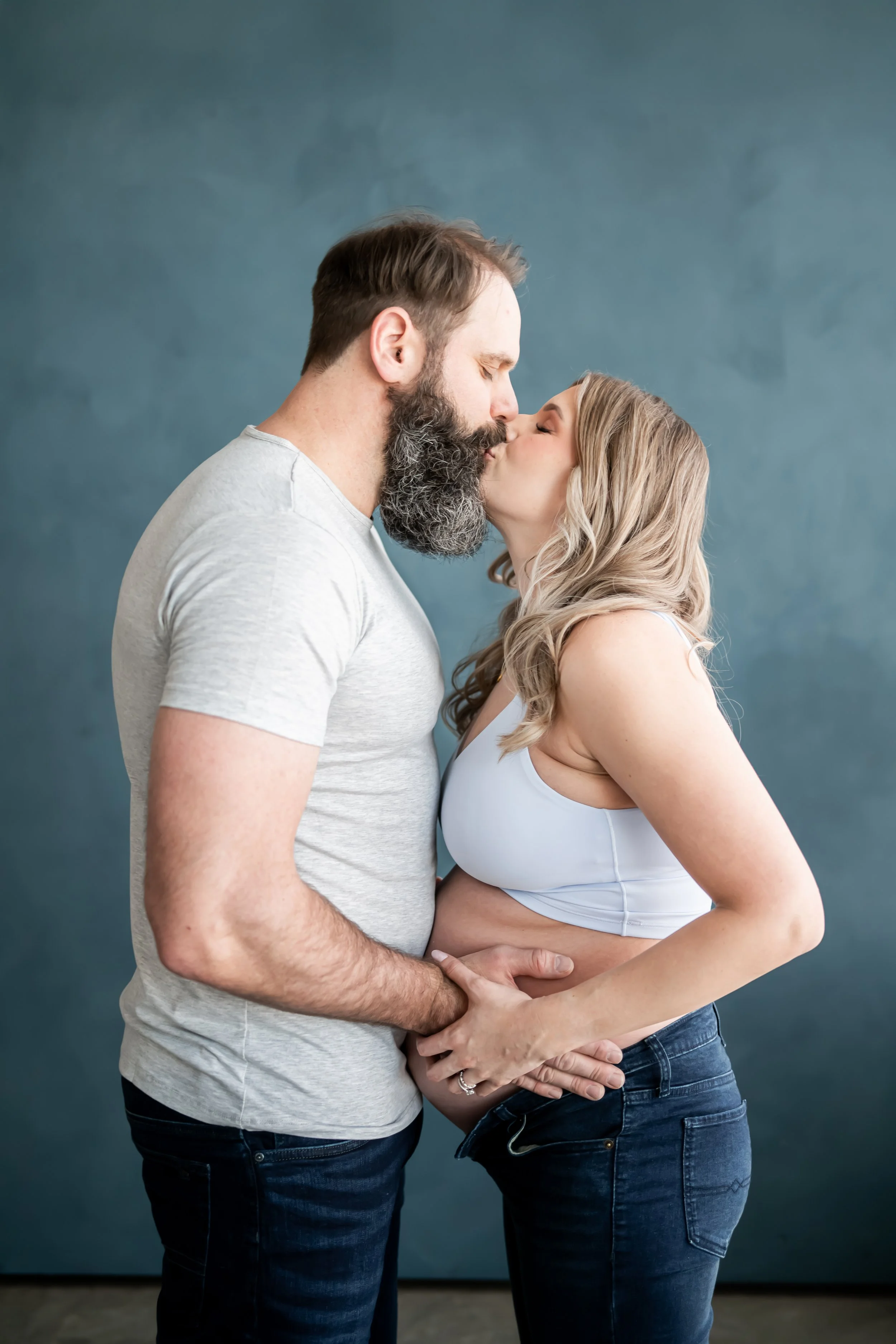 Elegant maternity portrait captured by a Calgary maternity photographer, featuring an expecting mother in a flowing gown holding her baby bump with soft natural light. A timeless pregnancy photoshoot celebrating motherhood and anticipation.
