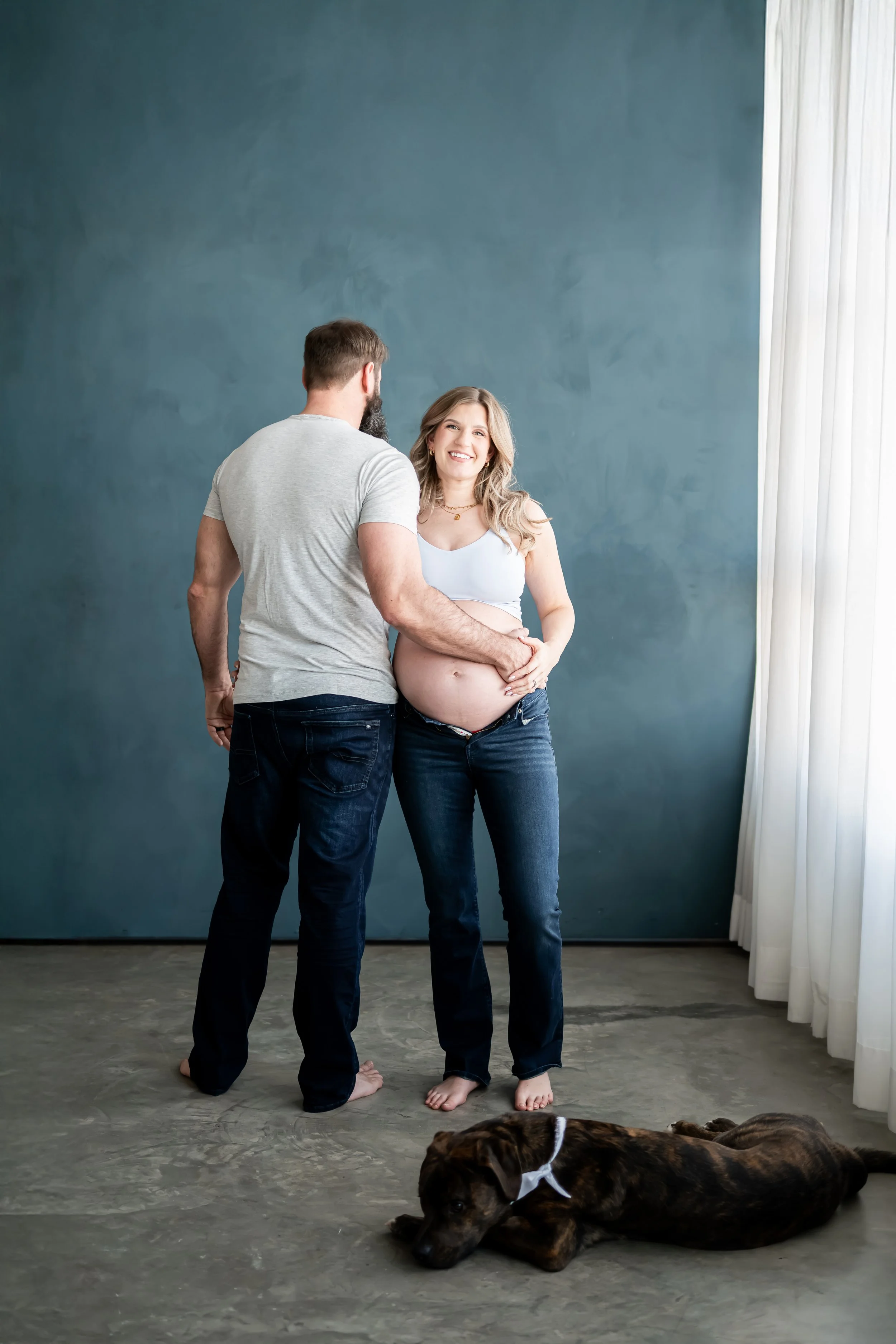 Elegant maternity portrait captured by a Calgary maternity photographer, featuring an expecting mother in a flowing gown holding her baby bump with soft natural light. A timeless pregnancy photoshoot celebrating motherhood and anticipation.