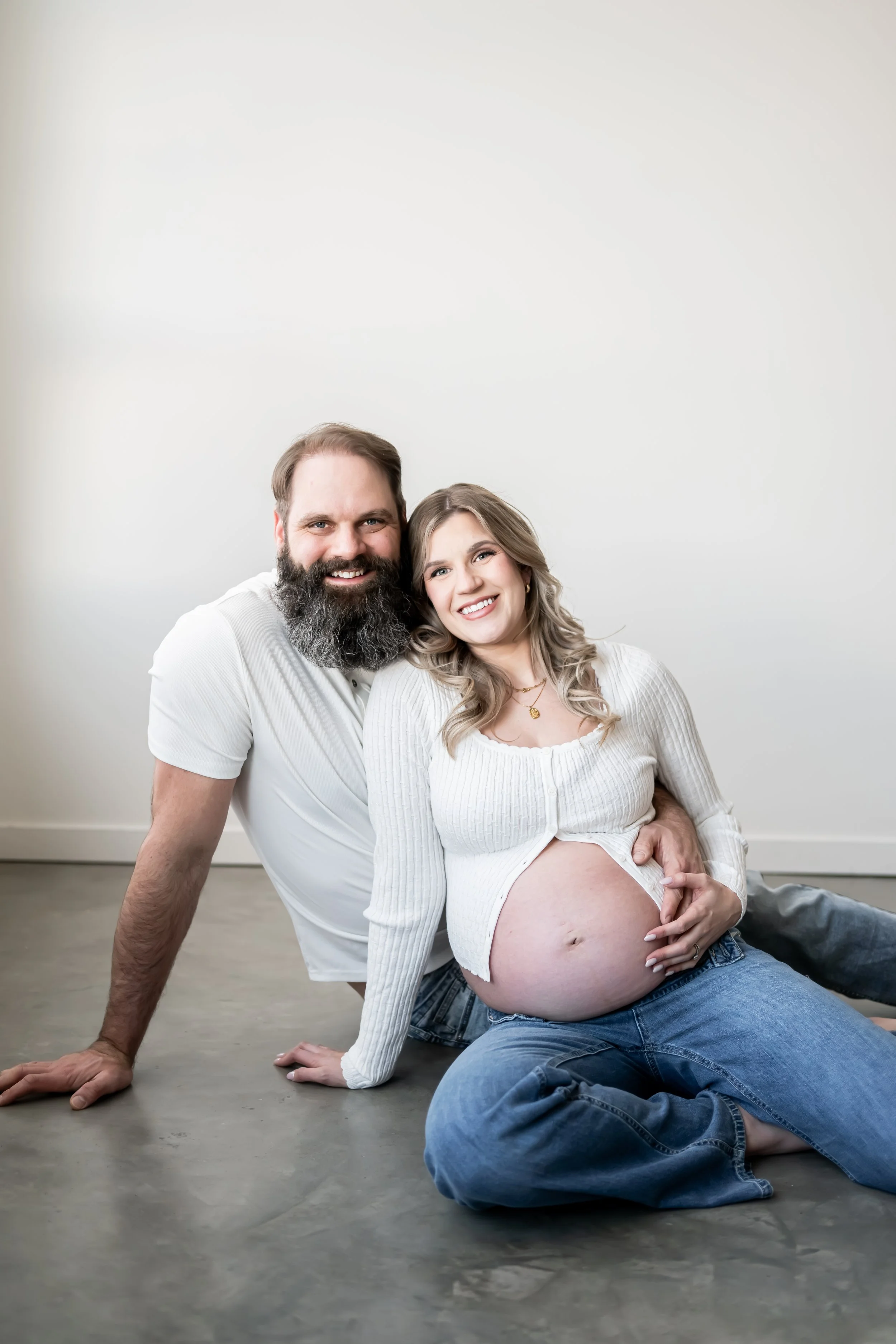 Elegant maternity portrait captured by a Calgary maternity photographer, featuring an expecting mother in a flowing gown holding her baby bump with soft natural light. A timeless pregnancy photoshoot celebrating motherhood and anticipation.