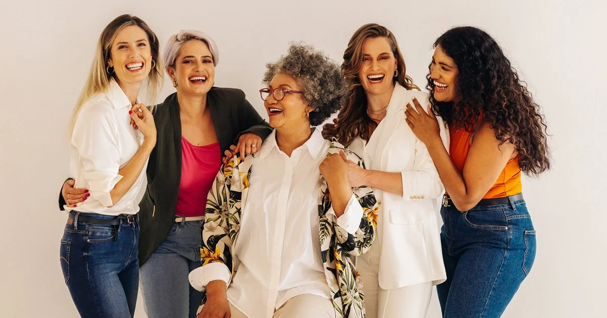 Five women laughing and smiling together against a plain white background: happy to be a part of the Biote experience!