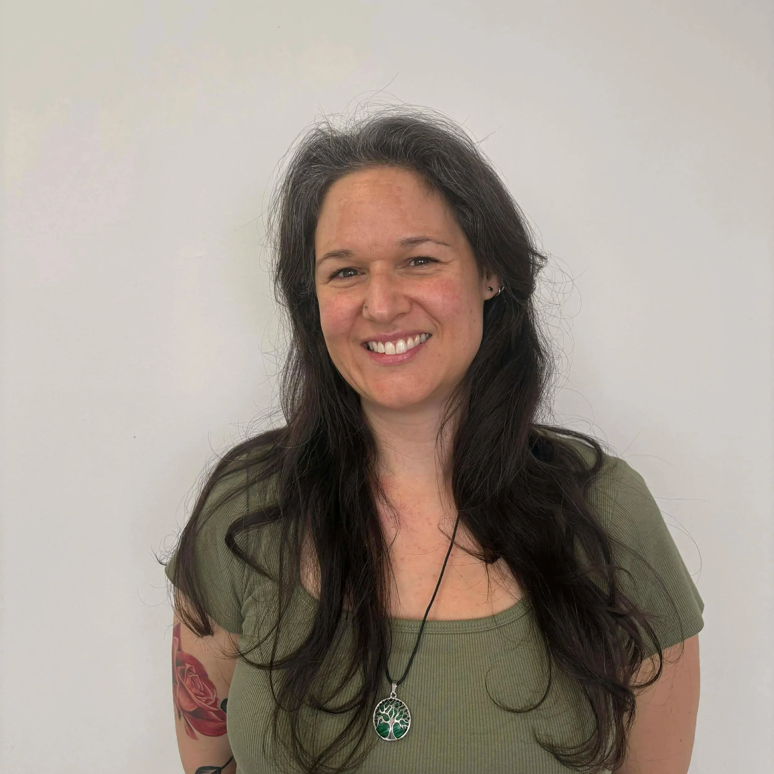 Alicia Patience, a female massage therapist in Calgary with dark hair smiling at the camera, with sparkles surrounding her in a photo with a plain background.