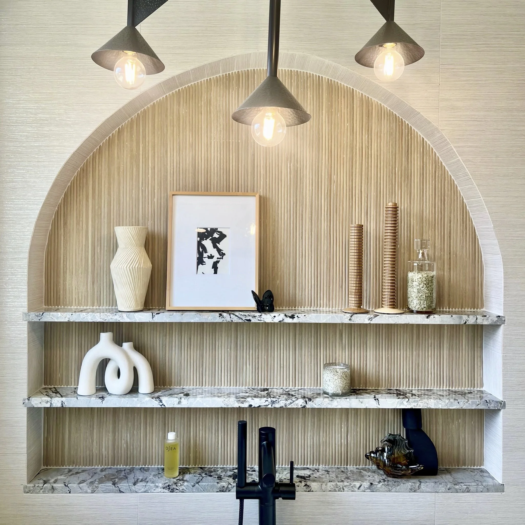 Multi-Niche Detail – Our custom niche design is the showpiece of the bathroom and features both warm and cool tones in the stone and tile. Decor is peaceful. And the light fixture overhead is artful