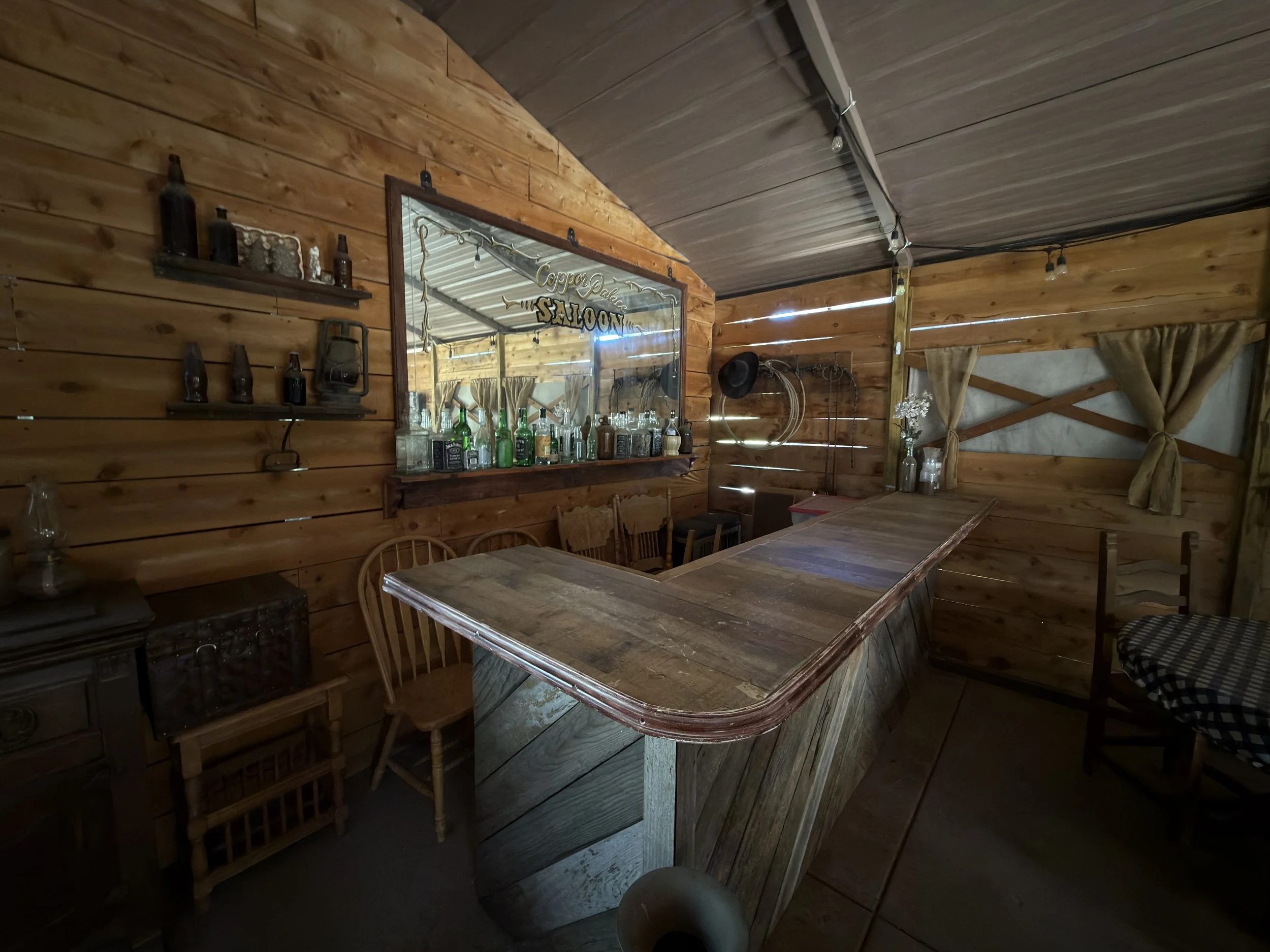 Location scouting photo of the wooden saloon bar counter and mirrored back bar lined with bottles on the On A Razor's Edge set.