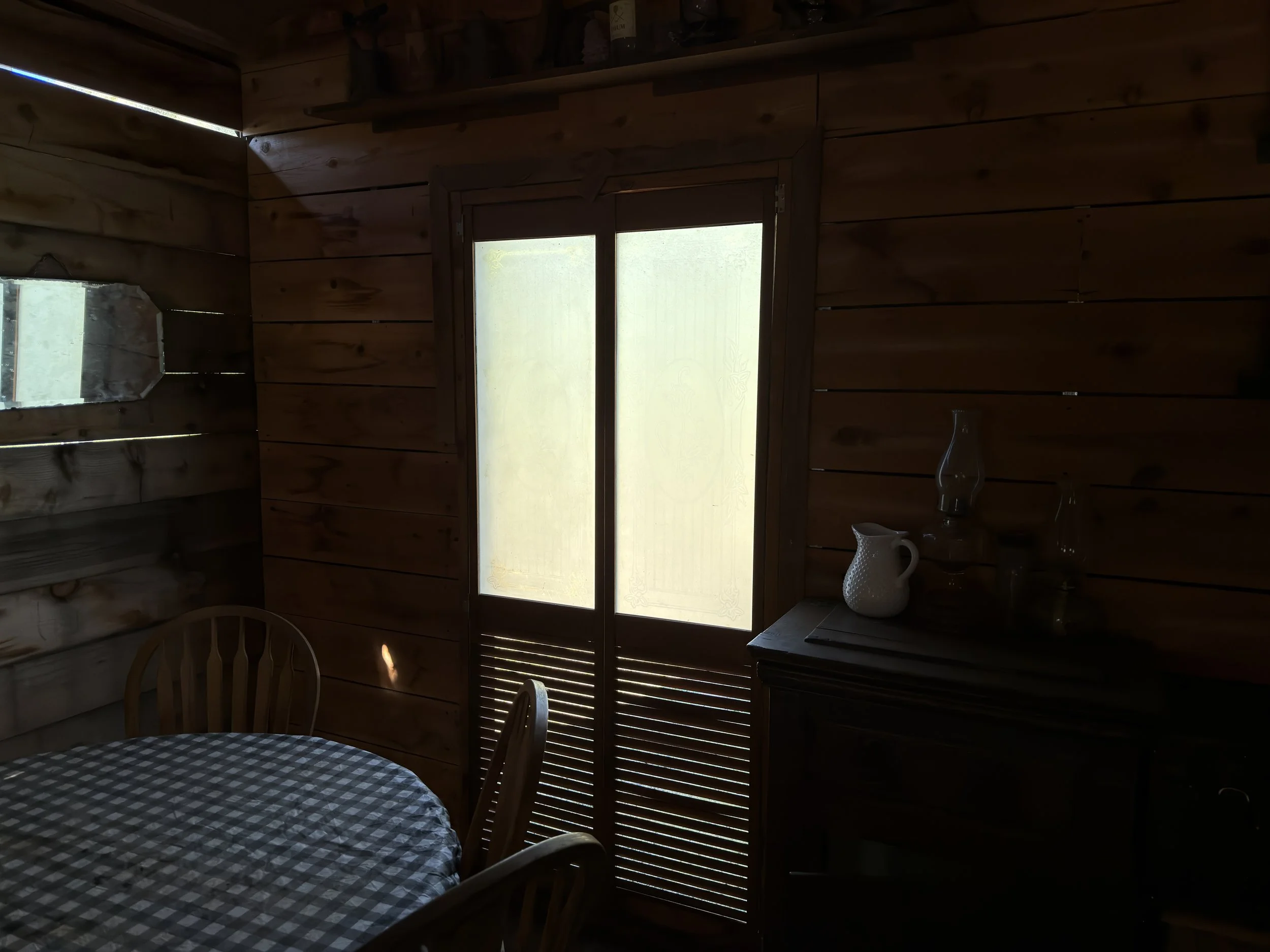 Location scouting photo of the On A Razor's Edge saloon set interior showing bright sidelight coming through a wood-shuttered window, illustrating the natural light the cinematographer planned to use.