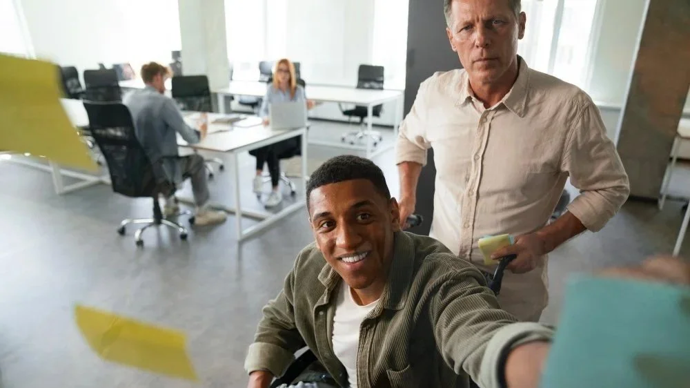 Man and coworker looking at sticky notes on their office wall