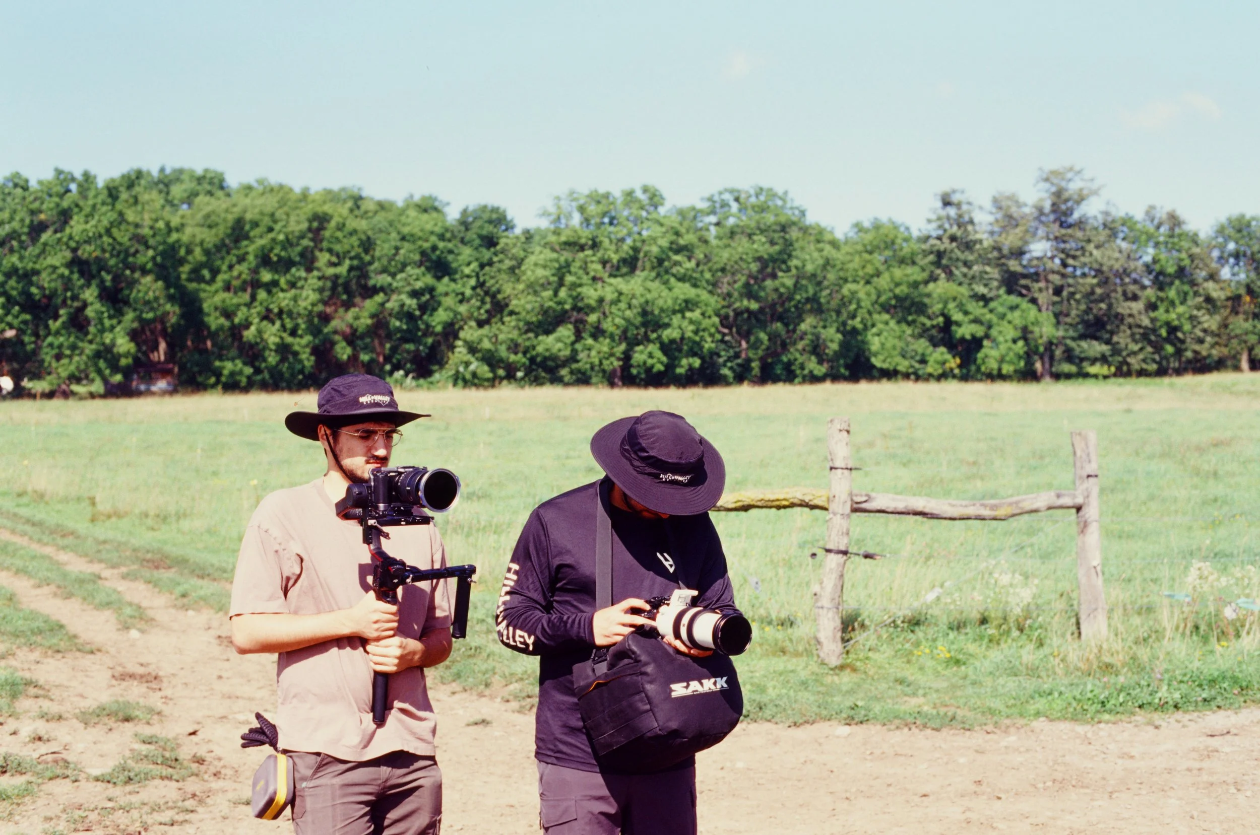 Two cinematographers filming with professional Sony video cameras on a farm outside