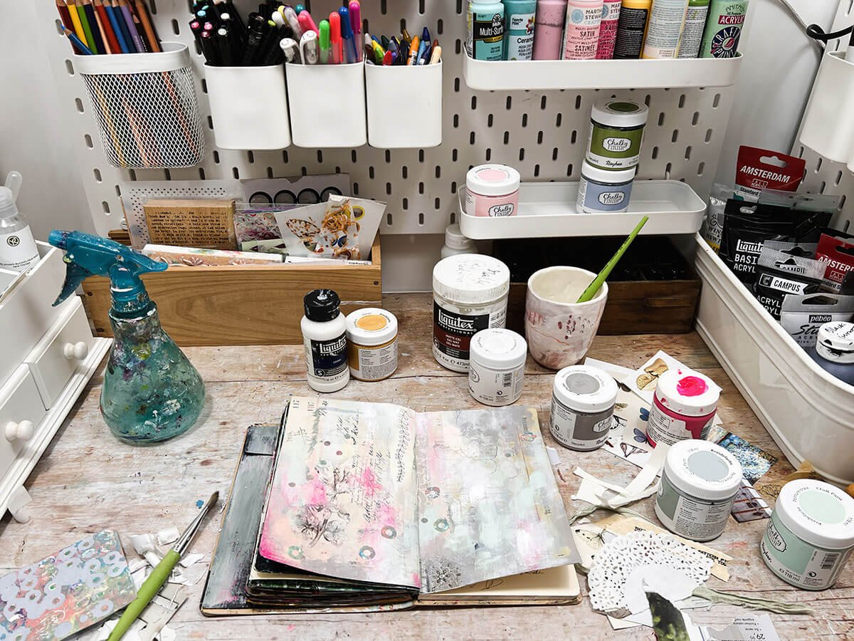 Small creative space with an art journal and vertical storage for paints, pens, pencils and crayons.