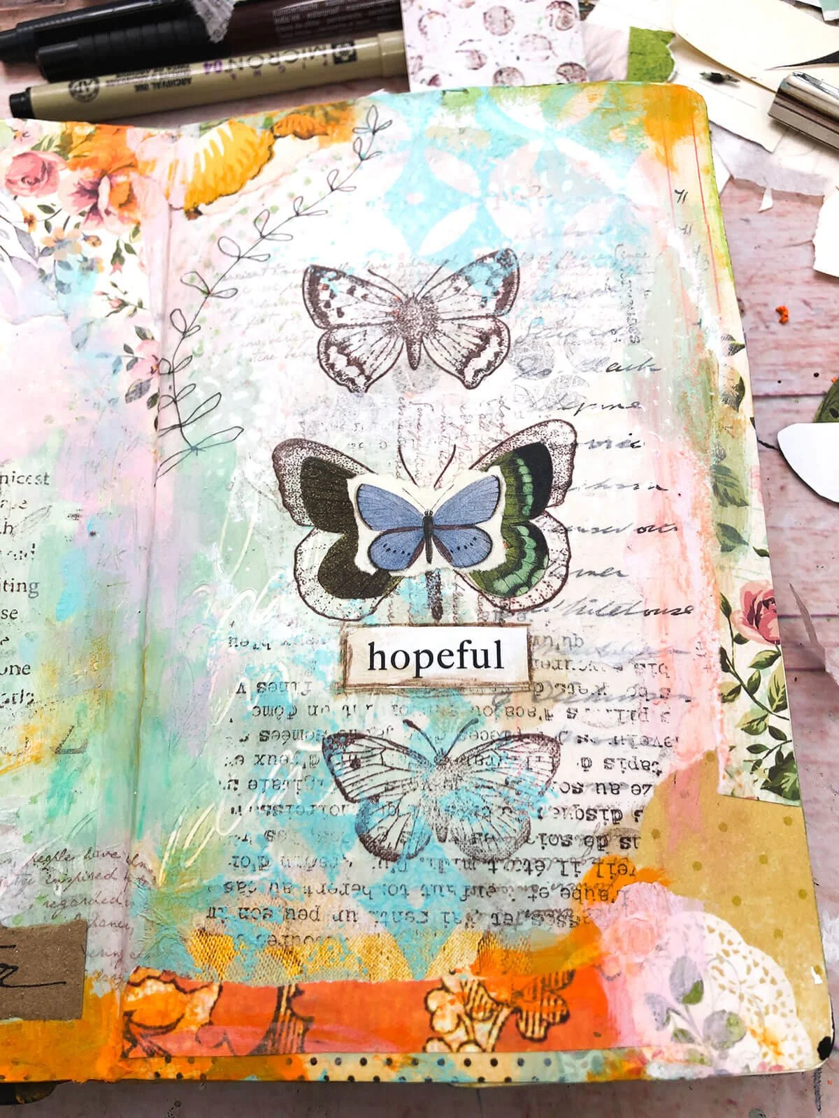 Art journal page with image transfers of butterflies, text and hand-drawn leaves.