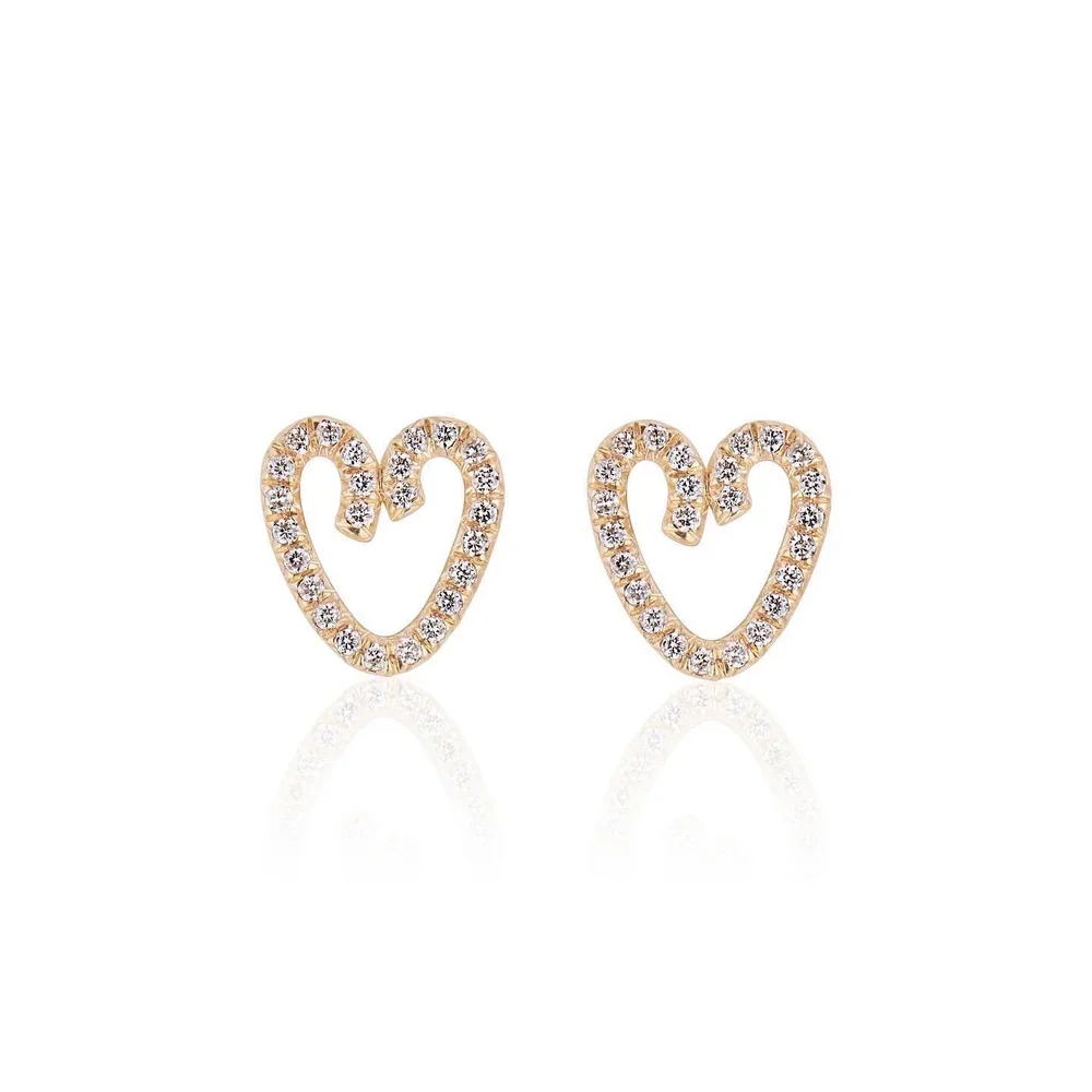 Gold heart-shaped earrings decorated with small diamonds, reflected on a white surface.