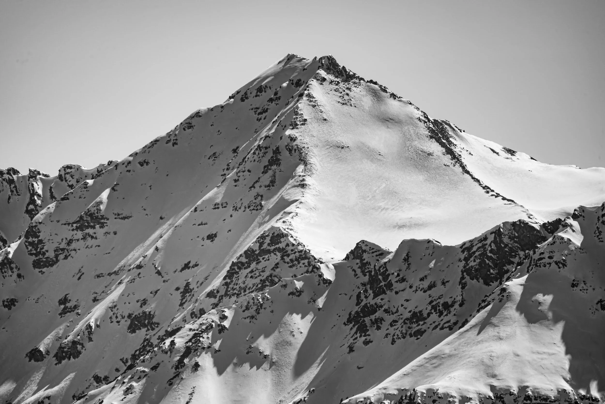 Snow-covered mountain with sharp peaks and ridges in black and white.