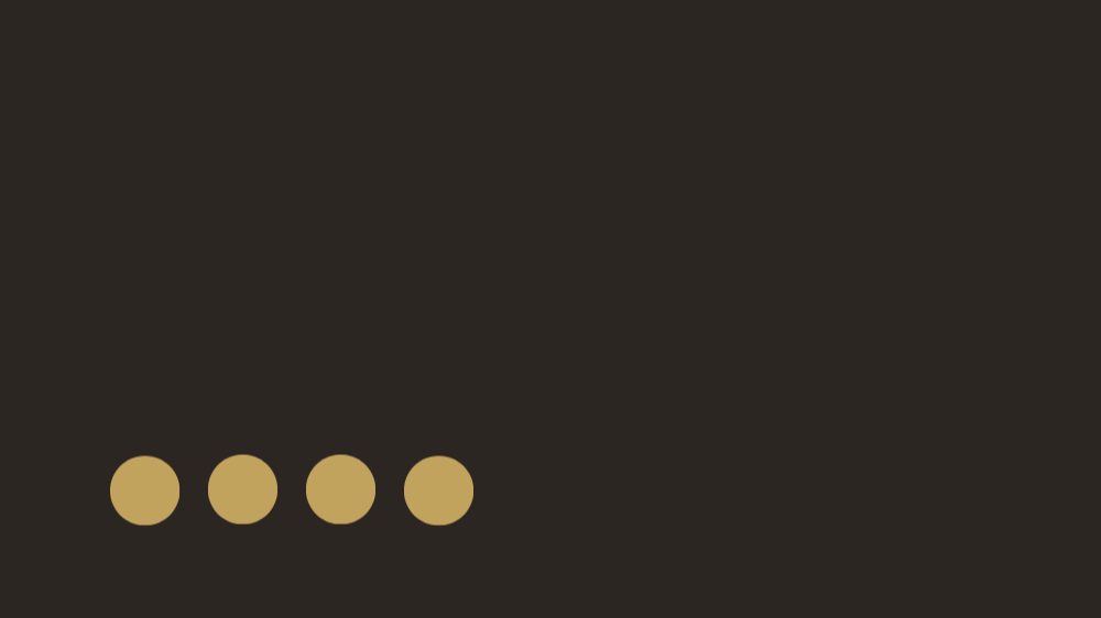 A close-up of a black surface with four gold-colored circular objects arranged in a horizontal line at the bottom left.