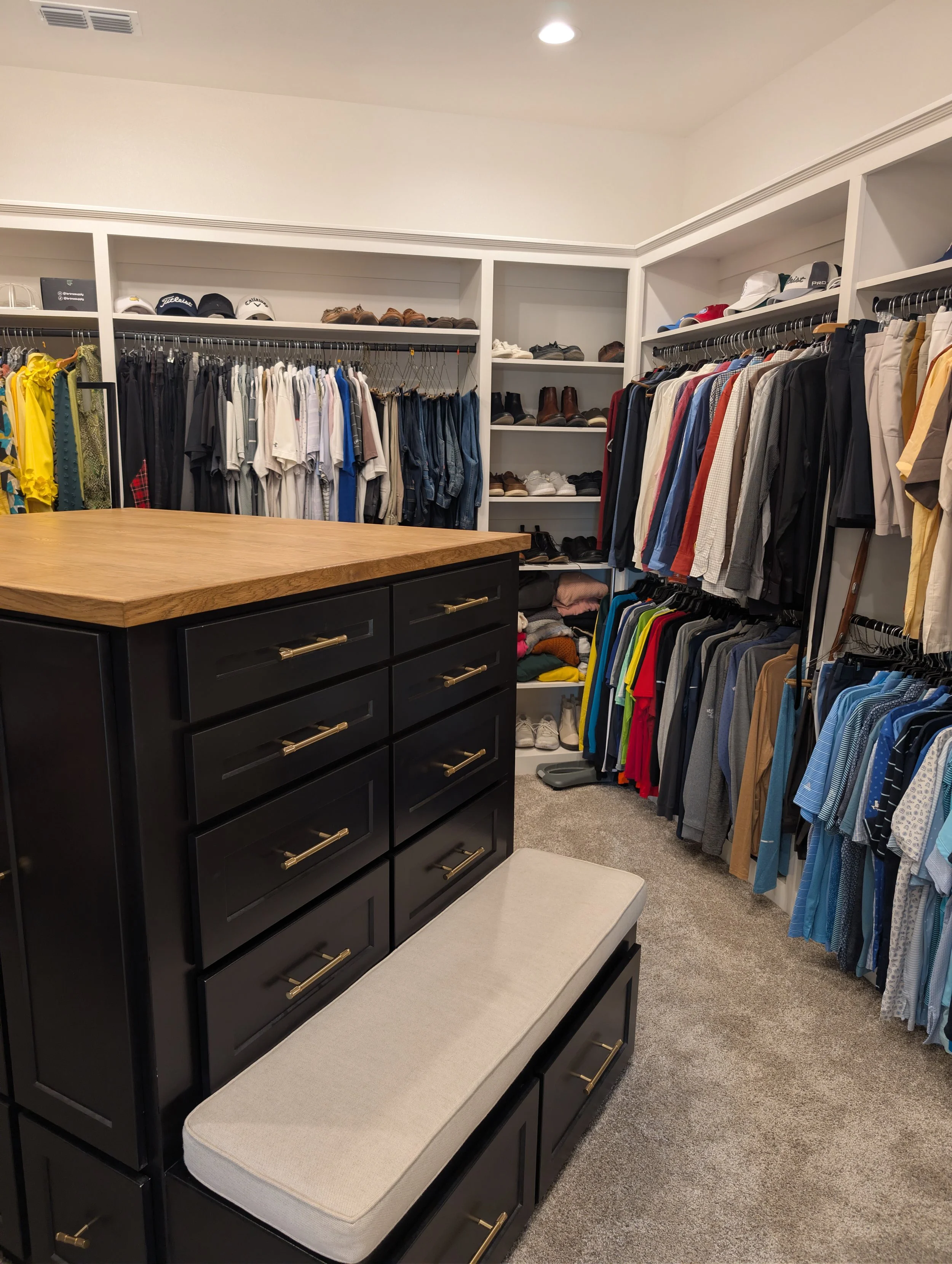 Custom closet with black painted island, white oak wood top, and clothes on black metal hanging rods