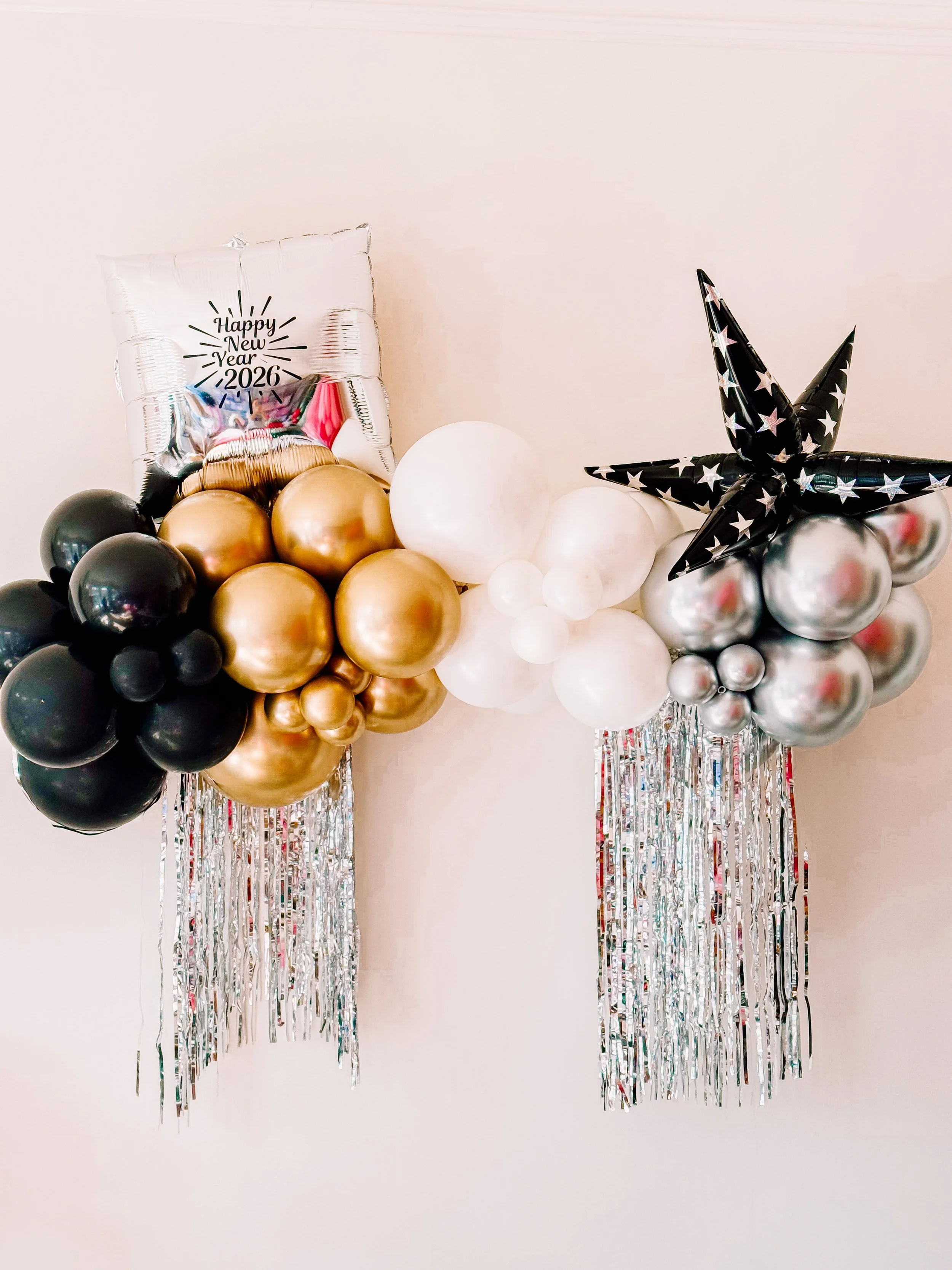 New Year’s Eve 5-foot balloon garland in black, gold, white, and silver balloons with metallic silver hanging tinsel, luxury party décor installation.