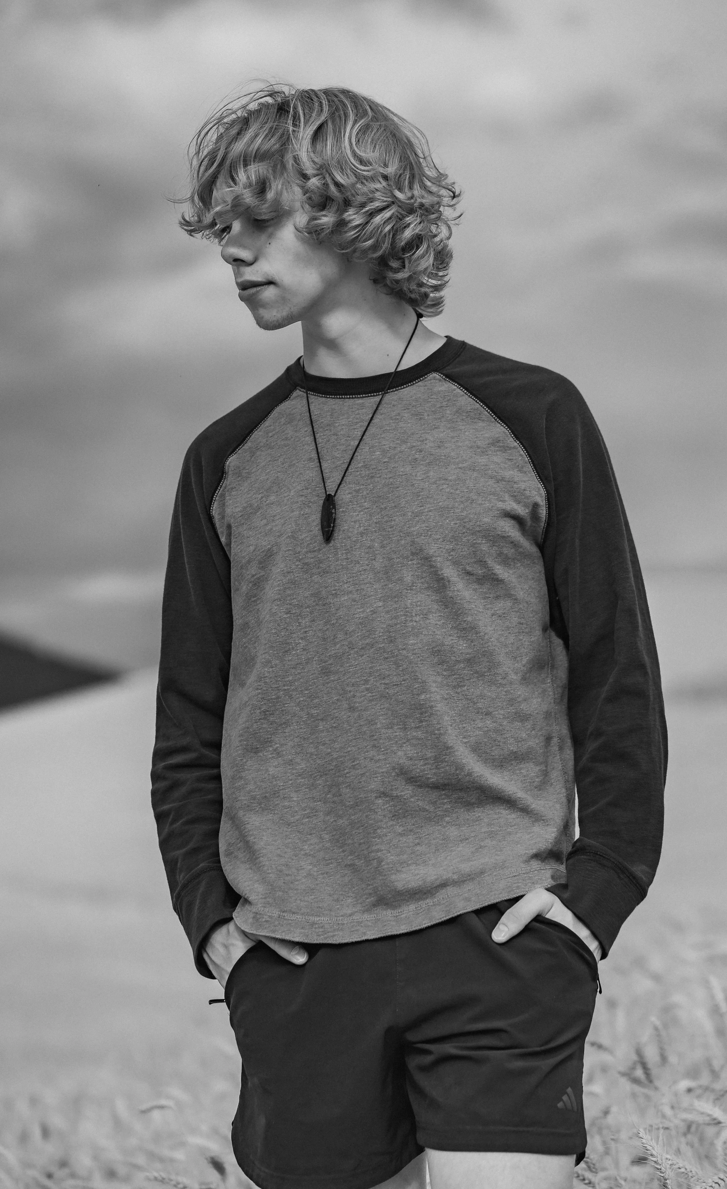 Senior boy standing in a field of wheat with stormy clouds.