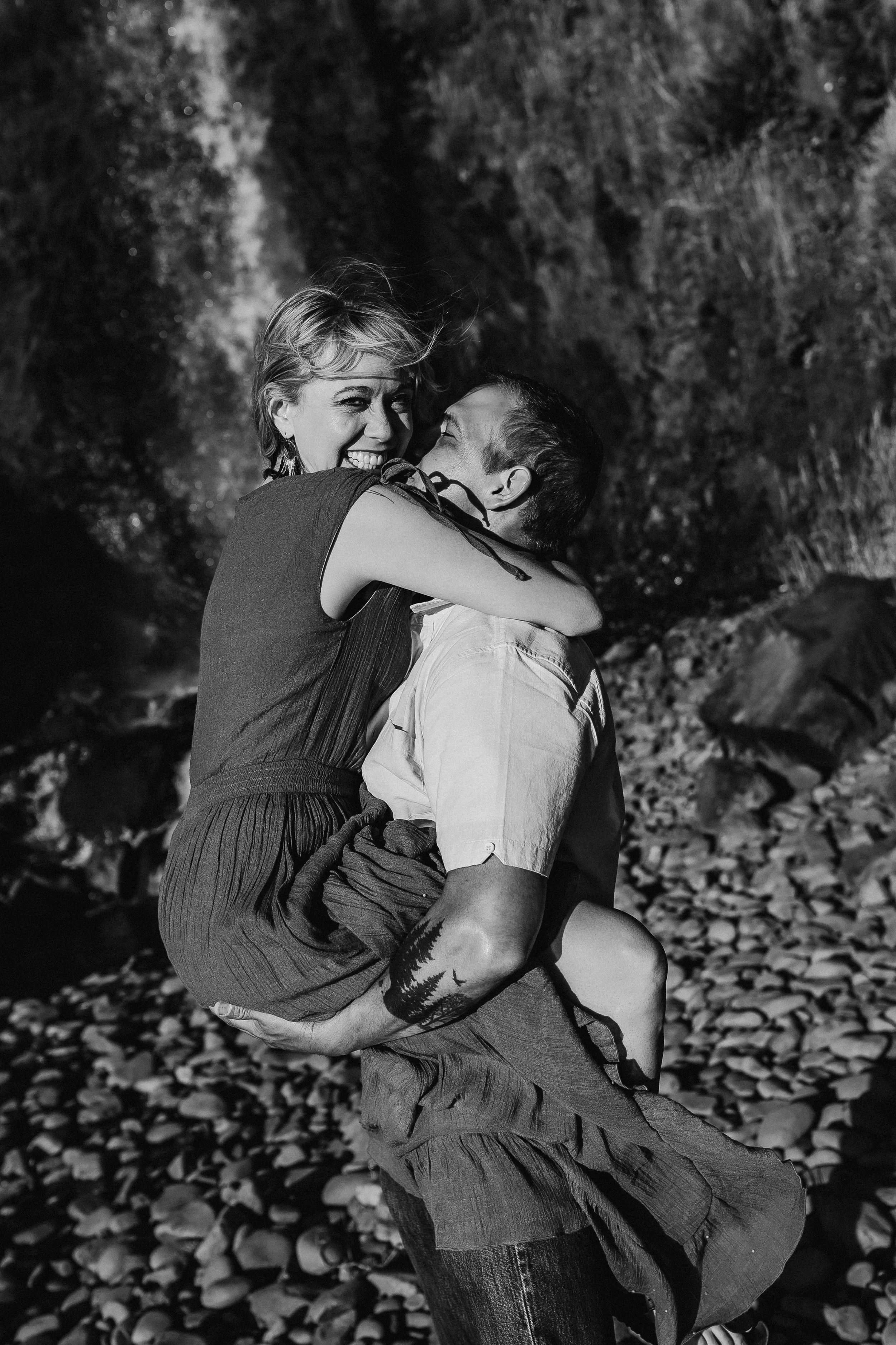Olympia Washington couple photographer.  Couple under waterfall. Washington Coast photographer. Man holds women up and carries her to the ocean. Couple poses. Thurston County photography. Tumwater. Lacey. Oregon Coast photographer.