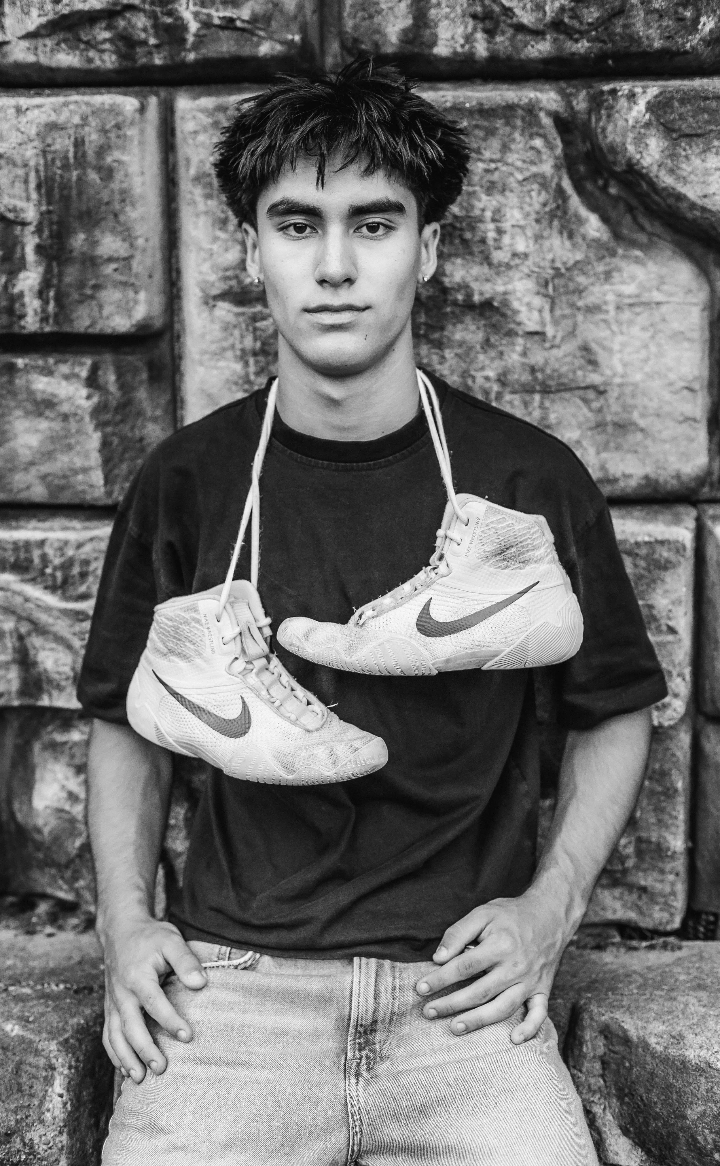 Senior boy posing with his wrestling shoes at Woodard Bay.