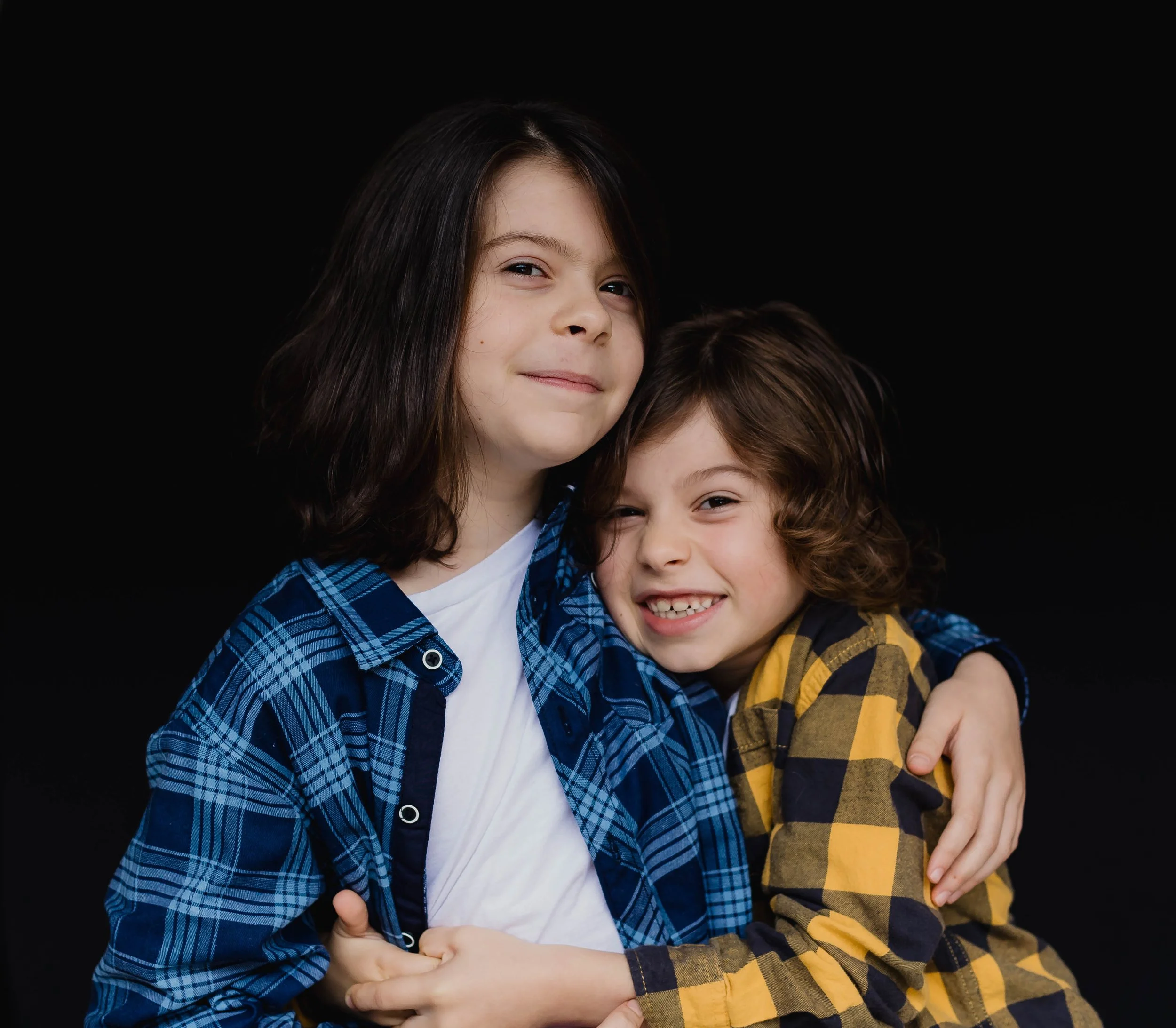 School photo of brothers laughing in blue and yellow flannel shirts and curly hair.