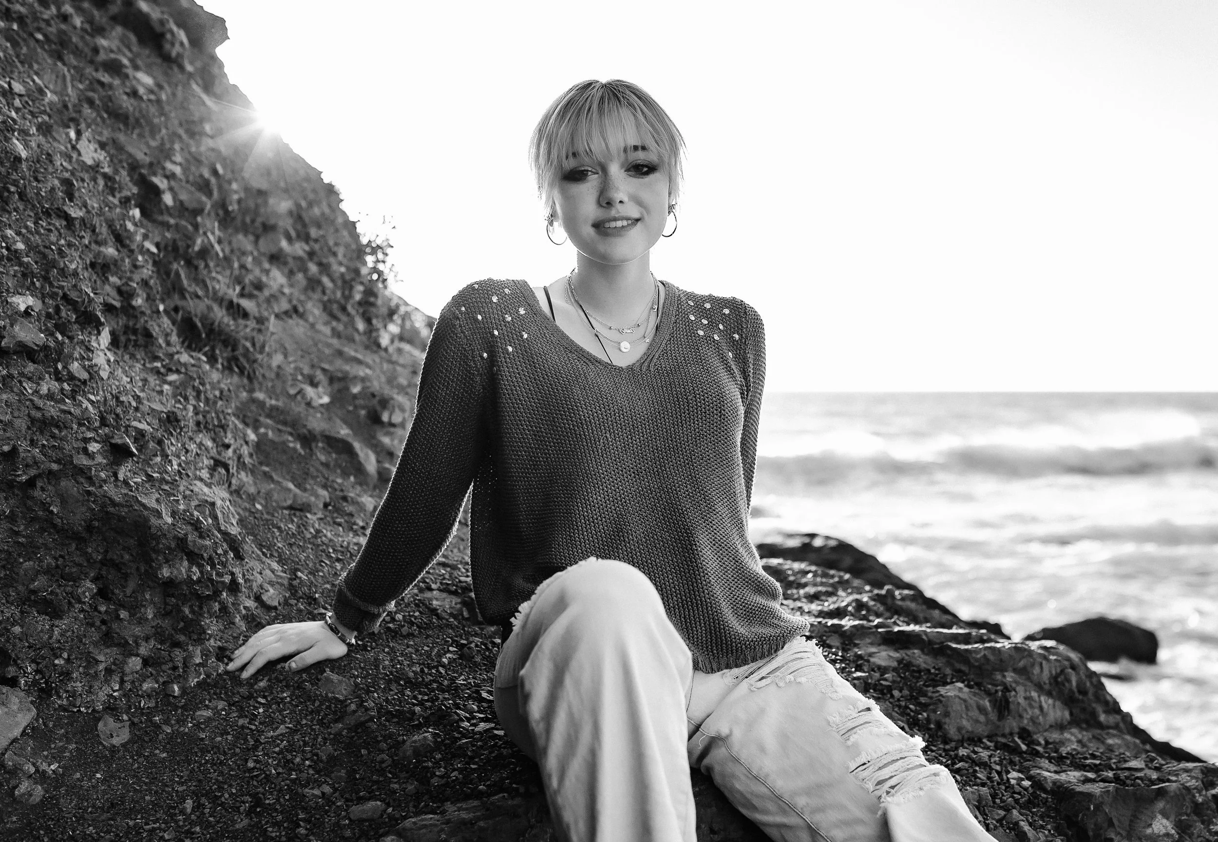 Beach portraits. Senior girl sitting on rocks at the Oregon Coast. Washington Coast. Nature portraits. Olympia photographer. Senior session at the beach. Tumwater. Lacey. Thurston County photographer. Sun flares. Pacific Ocean.