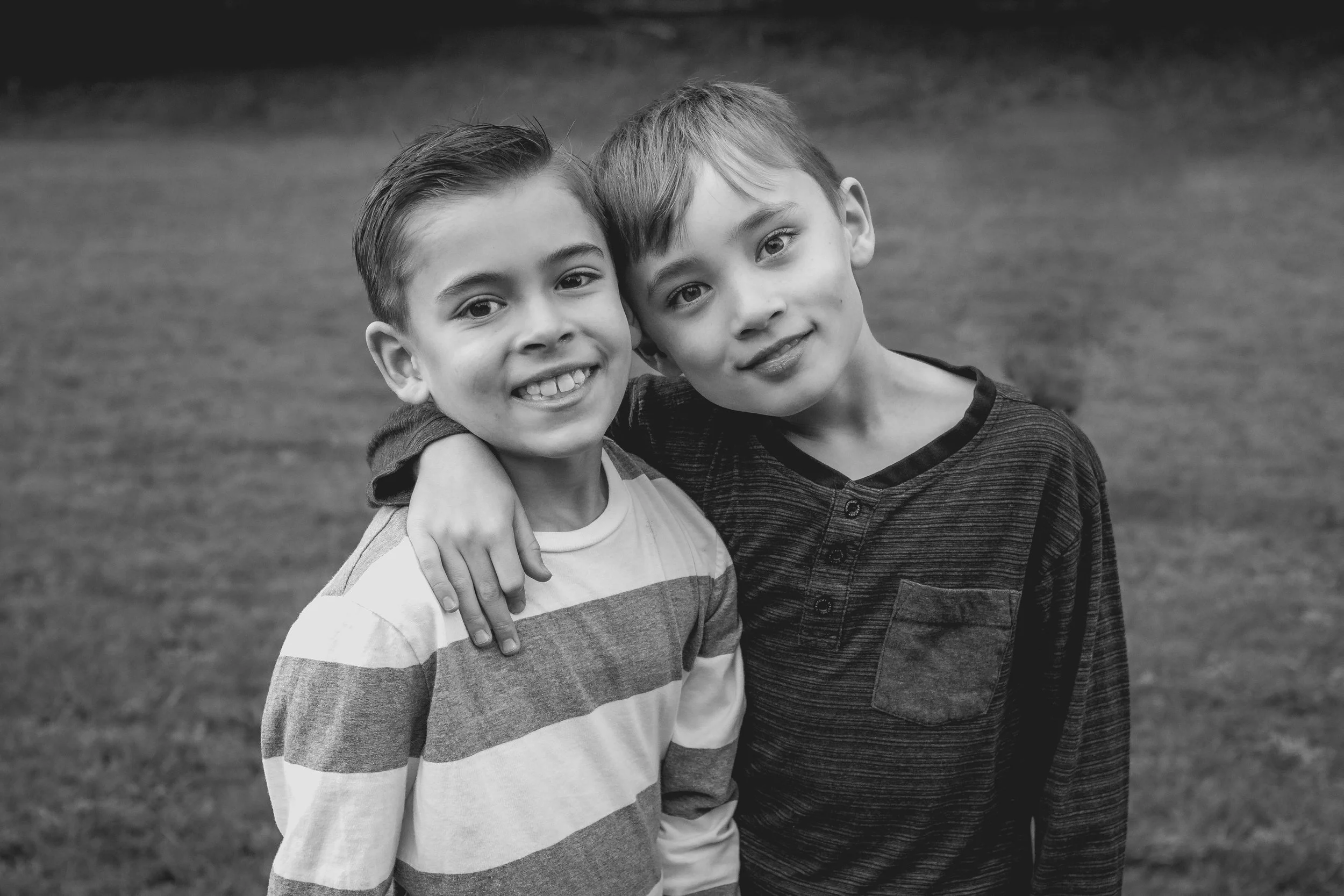 Extended family photoshoot with two boy cousins smiling at camera.