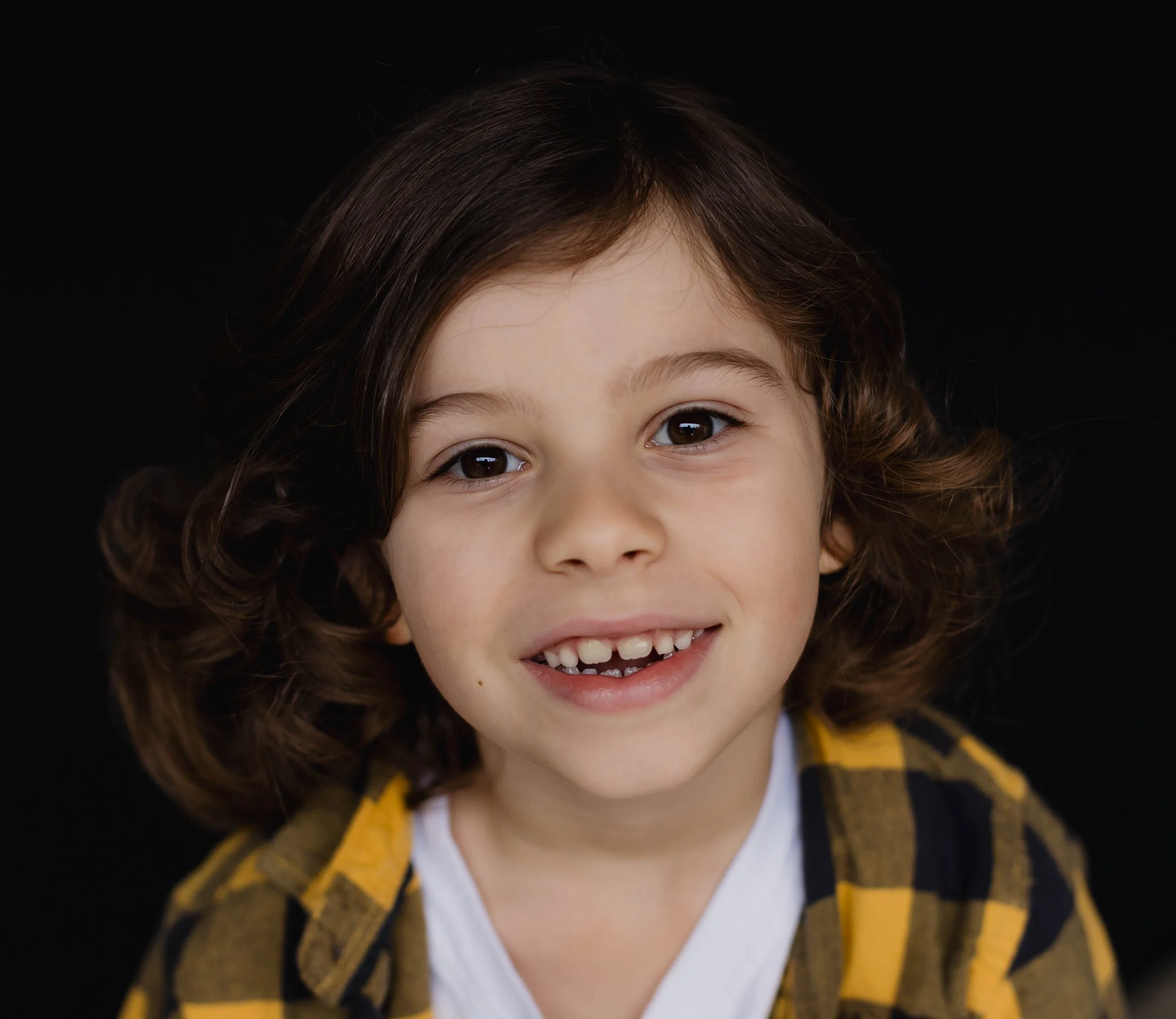 Smiling elementary school brown haired boy smiling authentically into the camera.