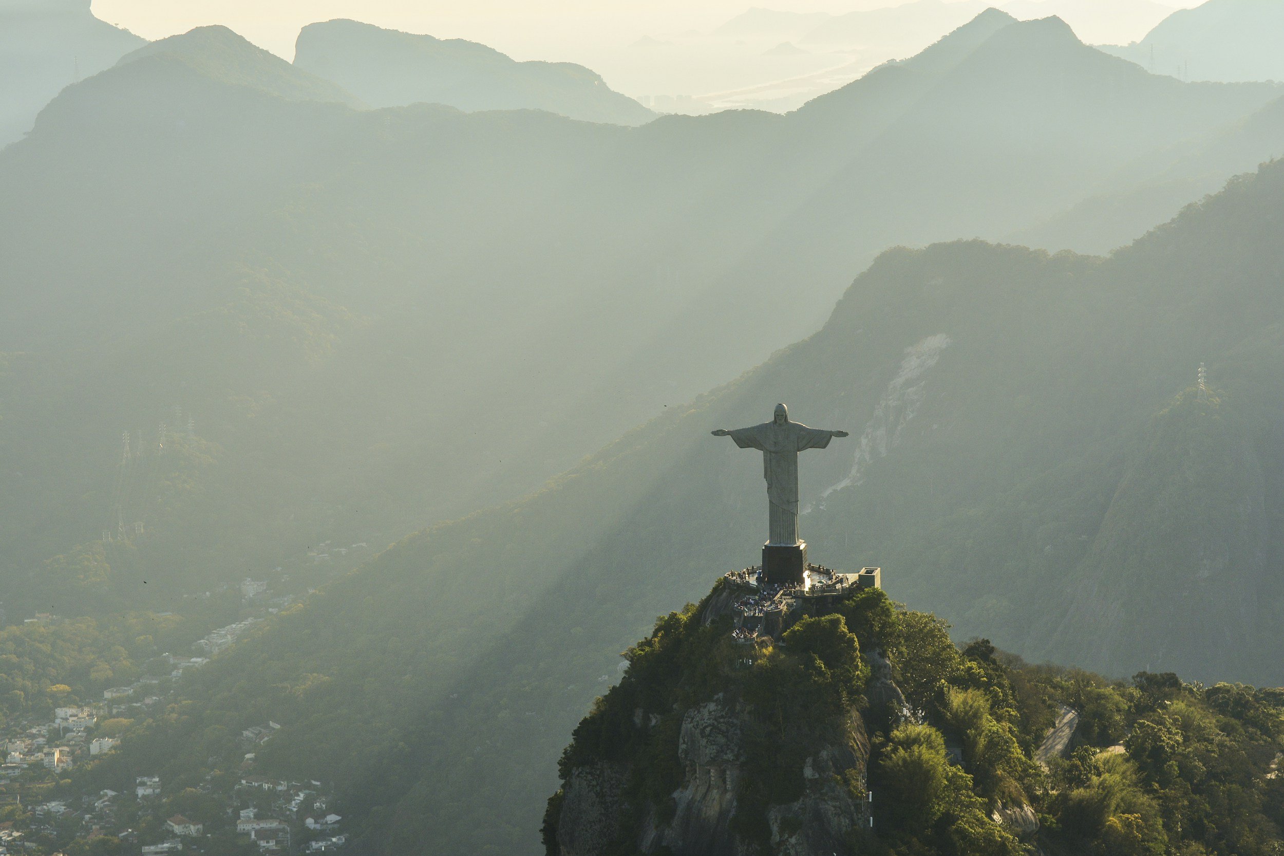View of Christ the Redeemer statue on mountain peak with surrounding misty mountains.