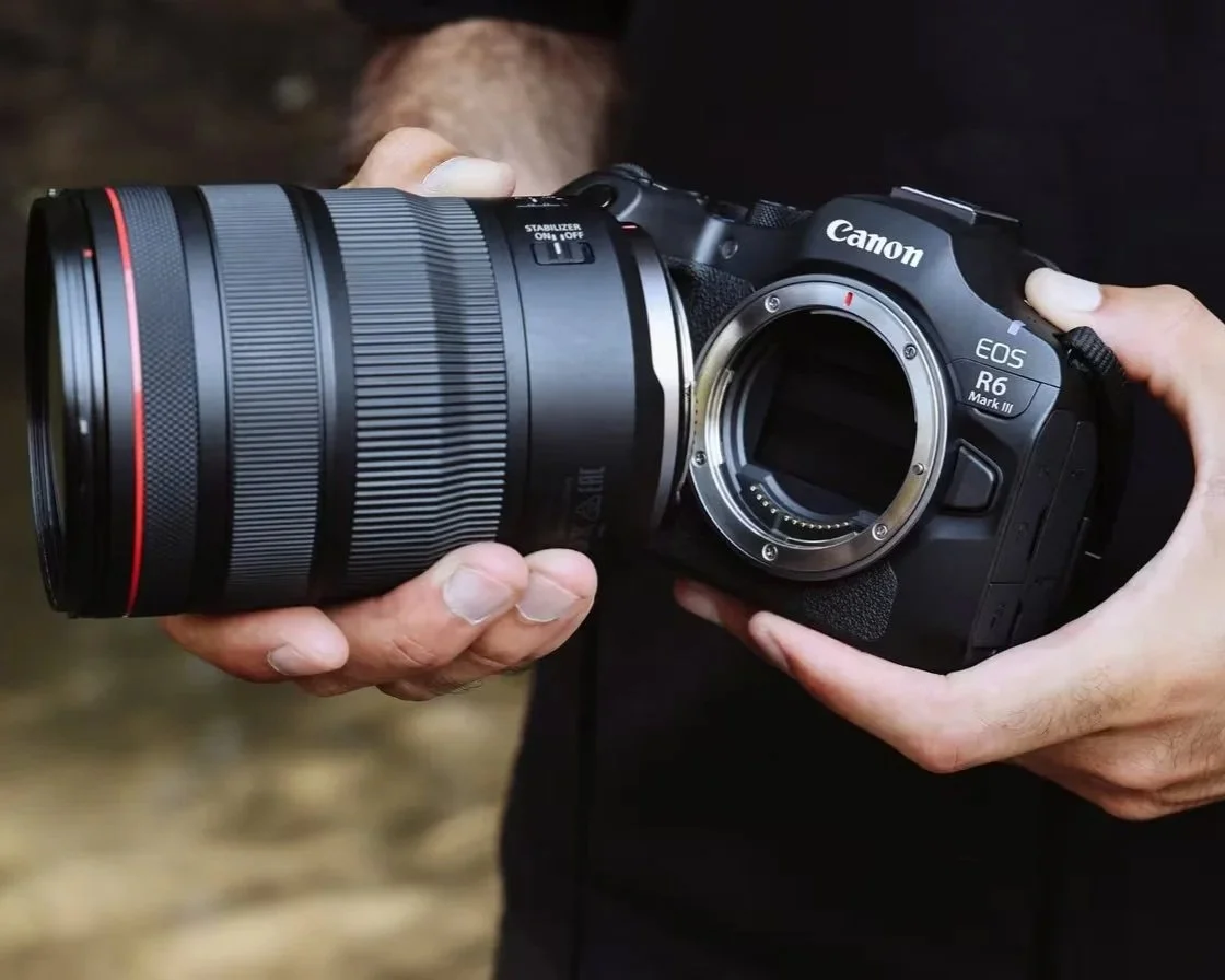 Person holding a Canon EOS R6 Mark III camera with a large lens attached