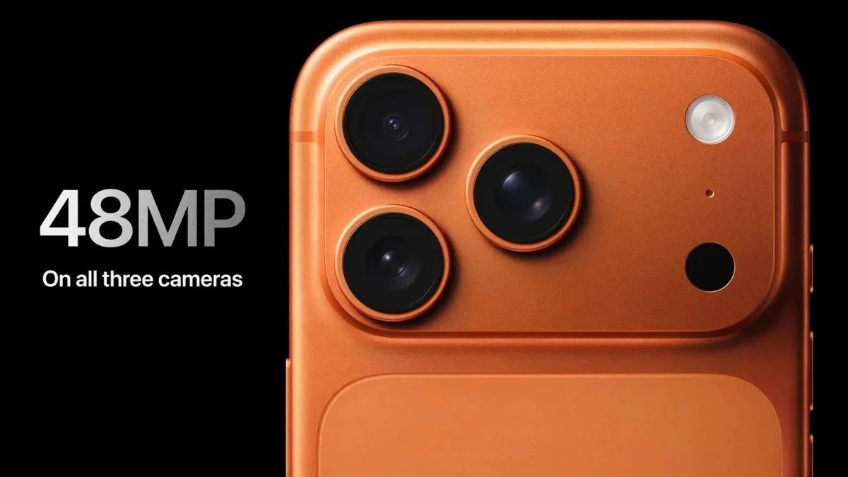 Close-up of an orange iphone showing three cameras on the back with 48 megapixels, along with a flash and other sensors.