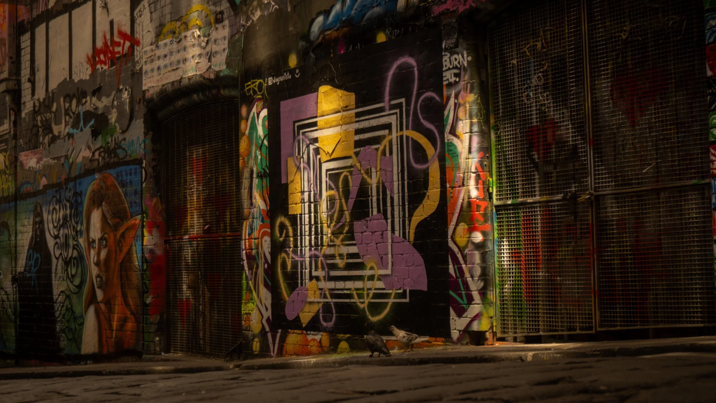 Graffiti-covered alley with colorful street art and abstract designs on walls.
