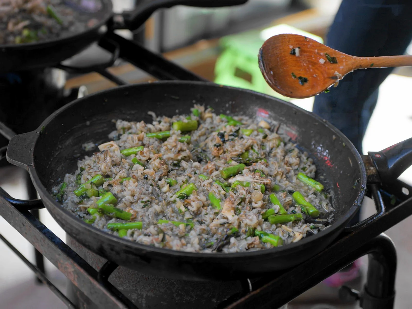 Cooking spring wild rice risotto with asparagus in a large skillet.