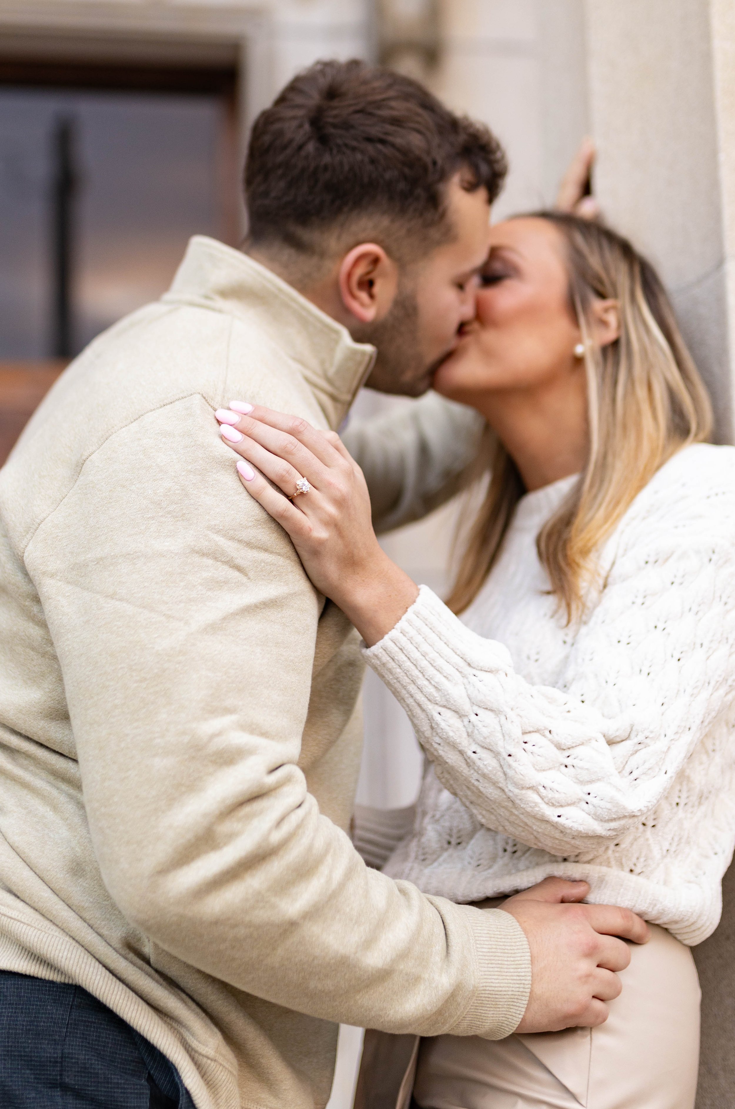 A couple sharing a kiss, with the woman showing an engagement ring on her finger.