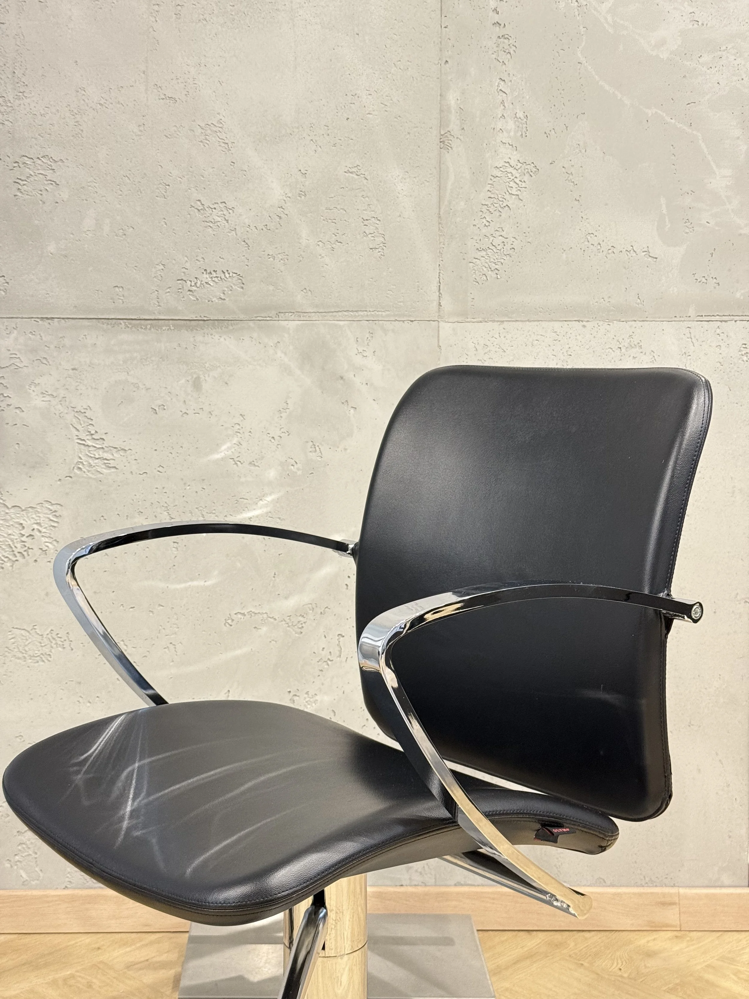 Schwarzer Salonstuhl vor heller Wand mit strukturierter Beton-Oberfläche