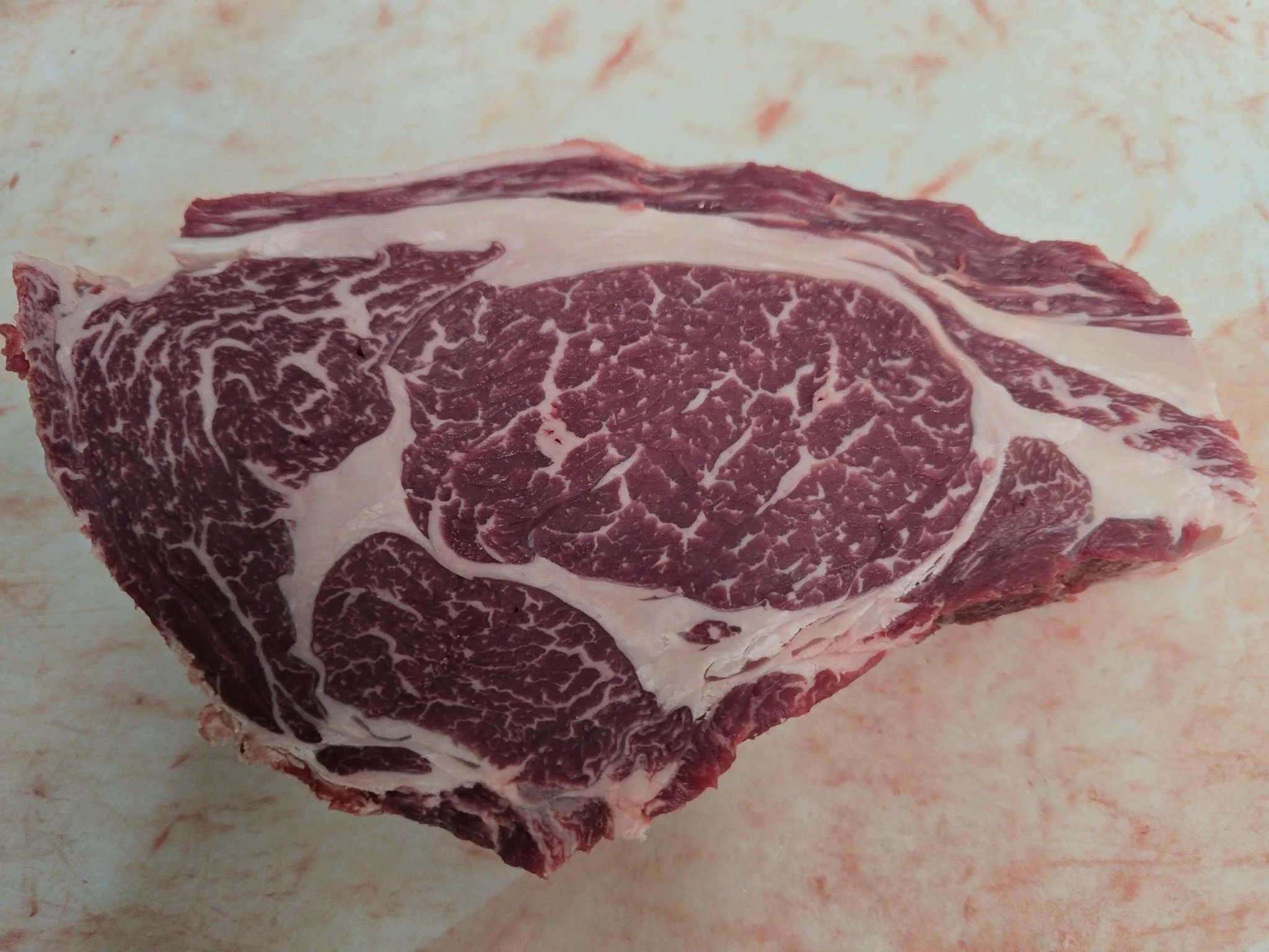 Close-up of a raw, marbled cut of beef with visible fat and muscle fibers.
