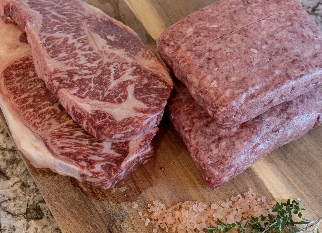Two raw chuck steaks on a wooden cutting board