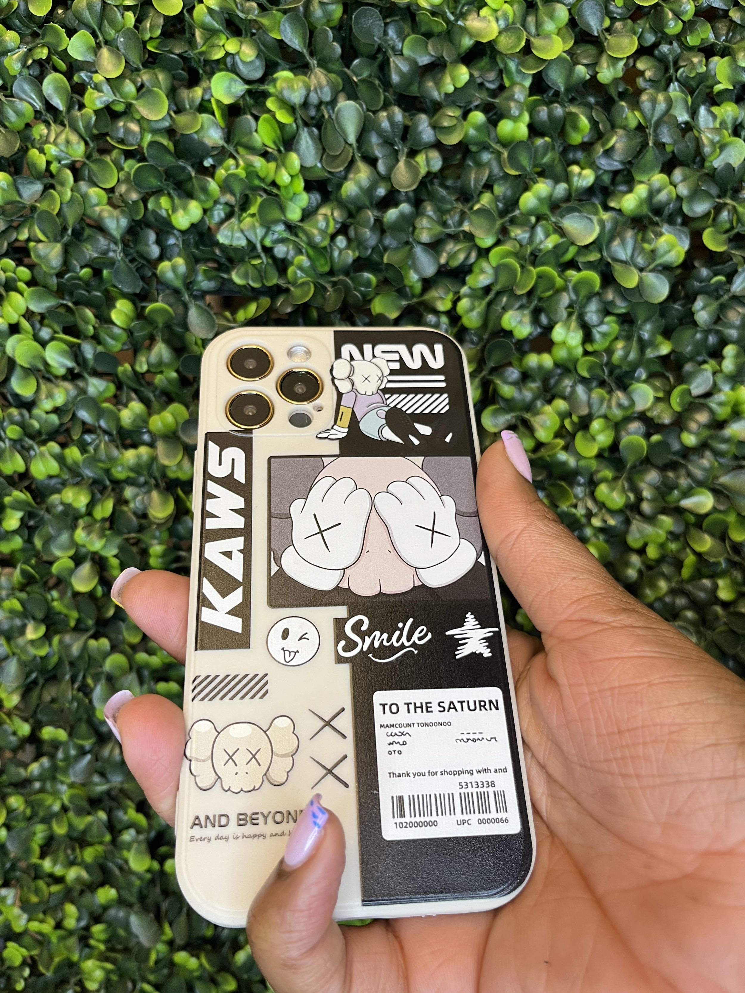 Person holding a decorated smartphone with stickers on a leafy green background.