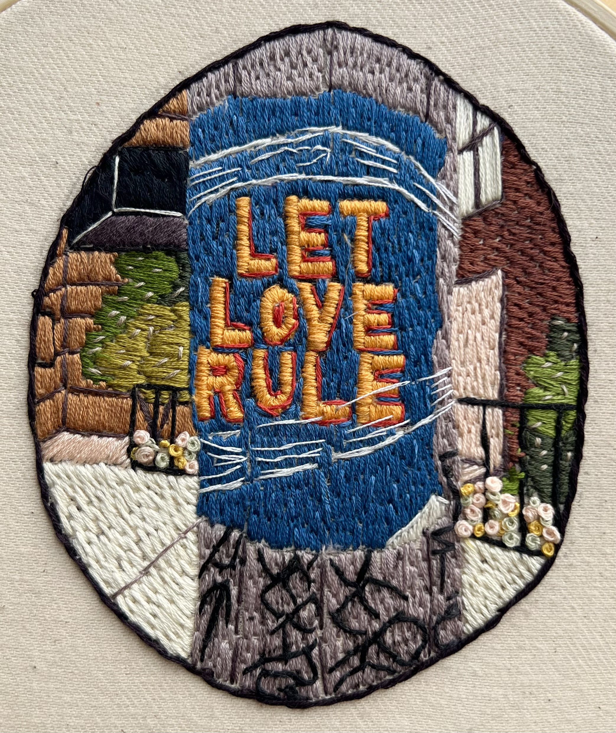 Let Love Rule embroidered patch photographed on studio canvas, inspired by public messages and the human instinct to mark belief.