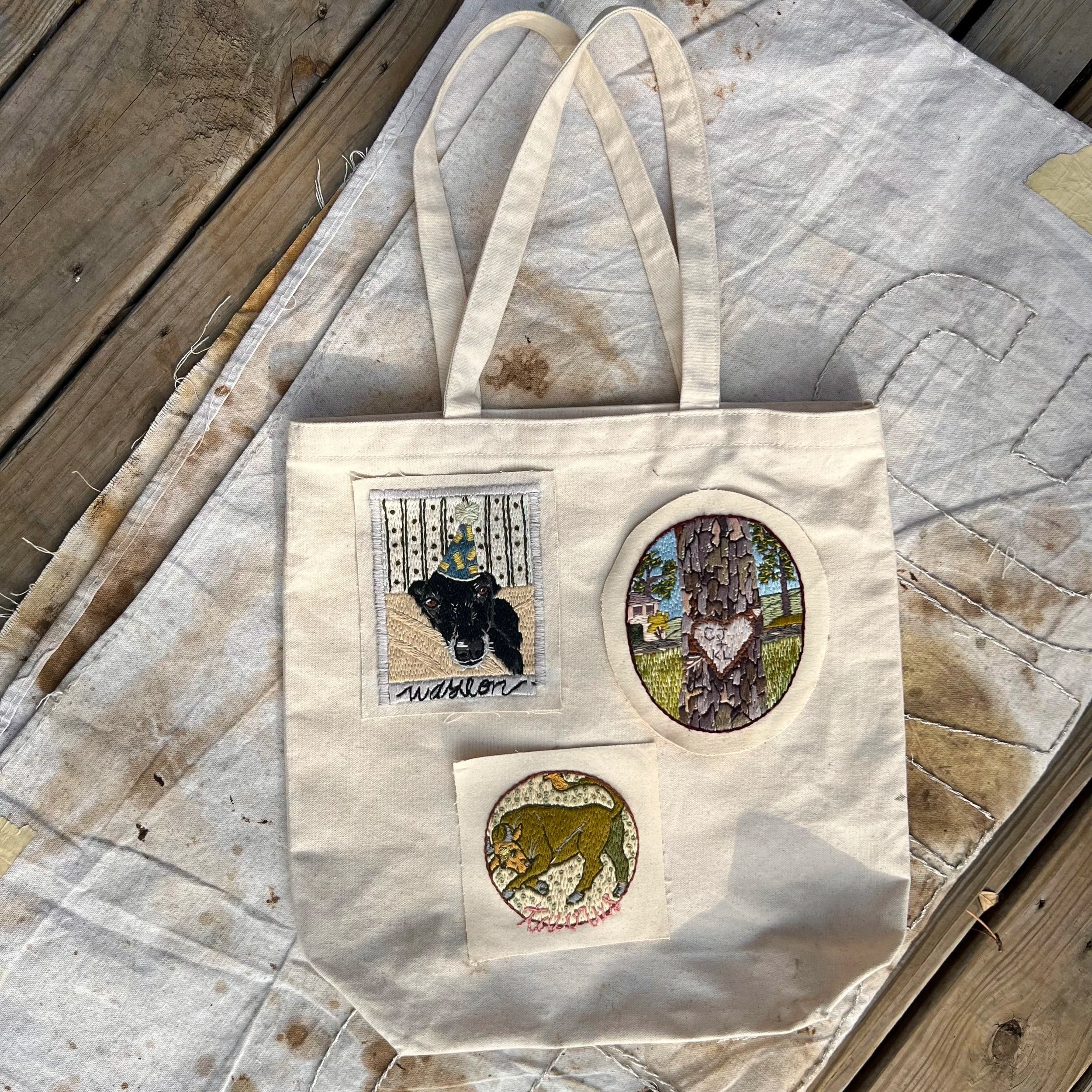 Canvas tote bag featuring hand-embroidered Mood Swing patches, including Arbor Glyph and custom pet portrait, designed to be collected over time.