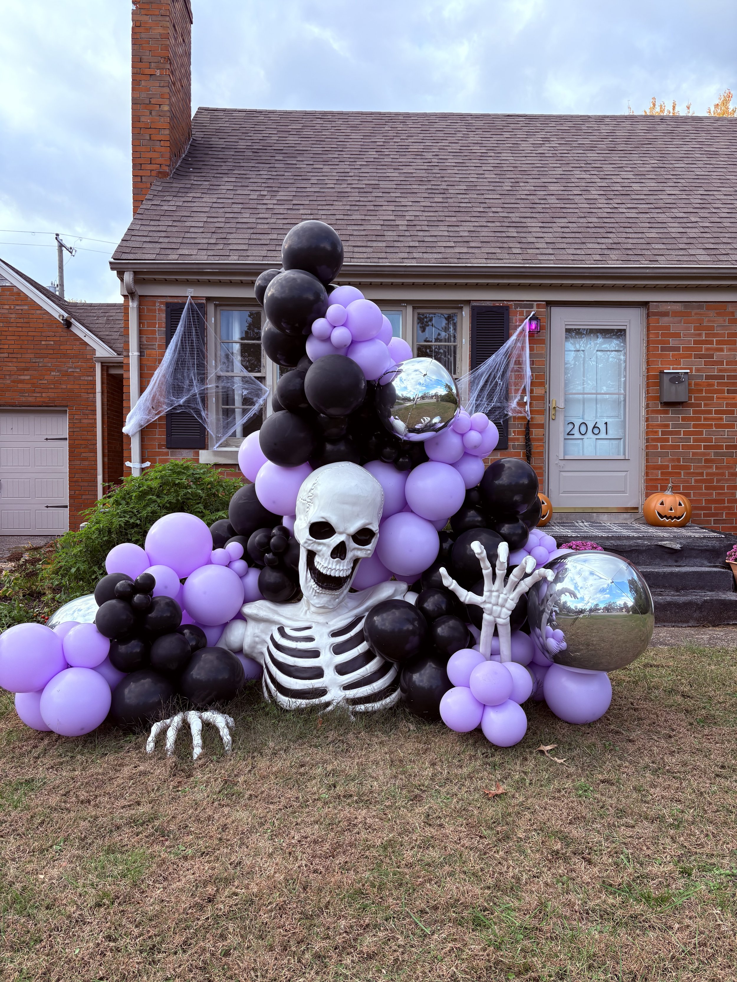 Colorful balloon garland in shades of pink and orange draped over a gray brick fireplace.