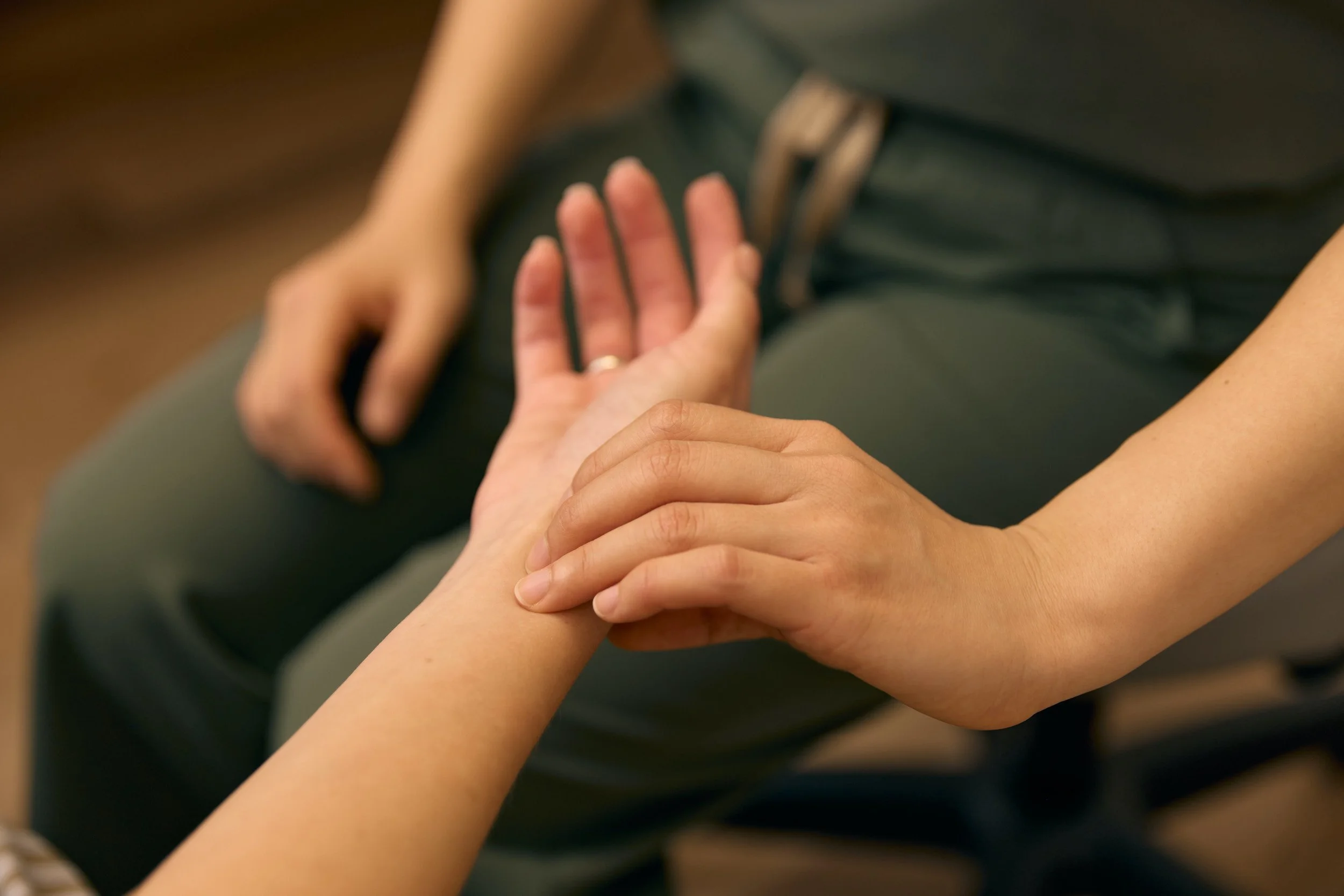 Close-up of Dr. Patricia Lee conducting a detailed assessment to evaluate a patient's pulse for fertility treatment.