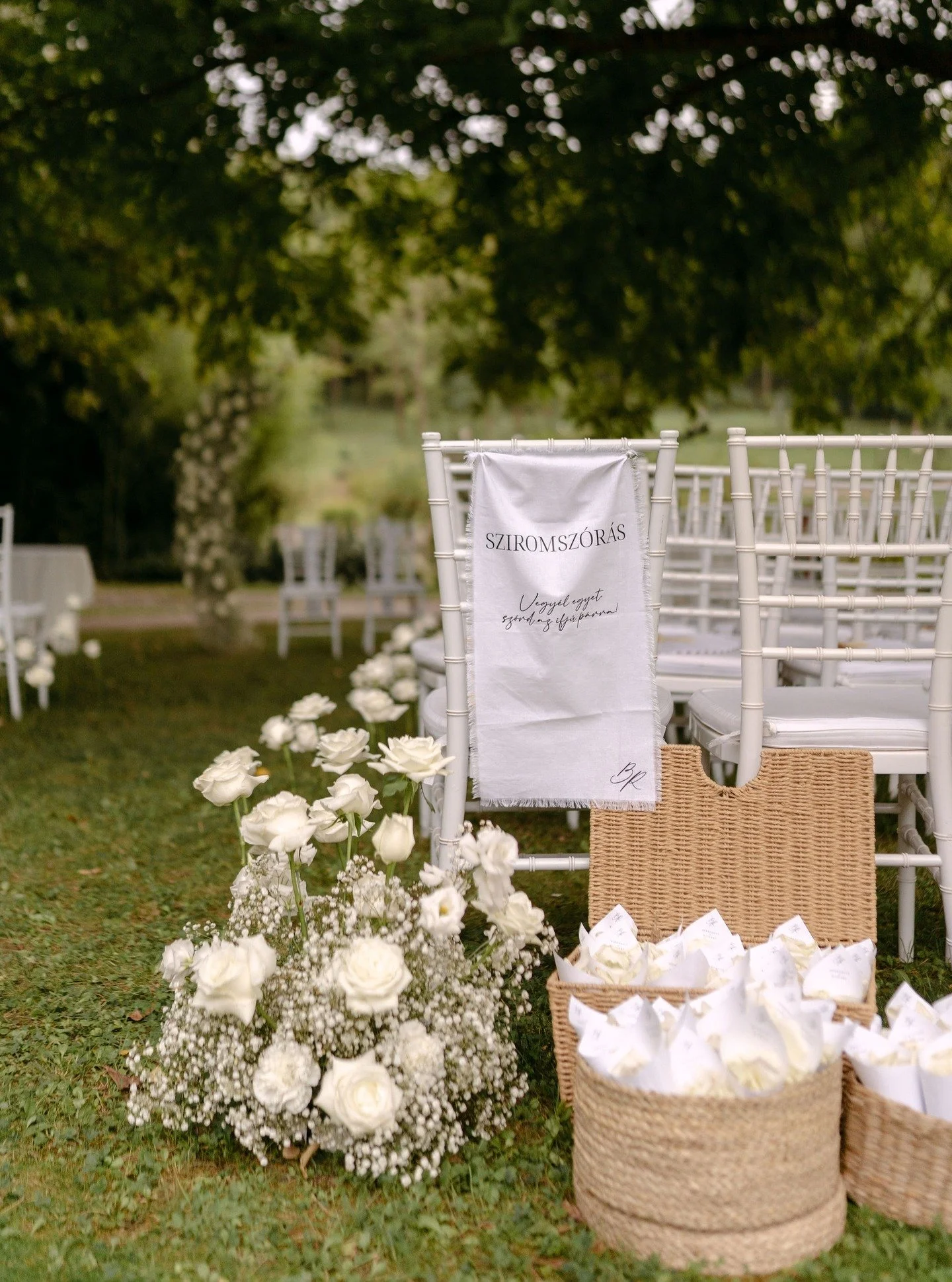 A sziromsz&oacute;r&aacute;shoz textil bannert k&eacute;sz&iacute;tett&uuml;nk, mellette pedig a r&oacute;zsaszirmok kaptak helyet, grafik&aacute;val ell&aacute;tott t&ouml;lcs&eacute;rekben, bek&eacute;sz&iacute;tve a vend&eacute;geknek. A szertart&