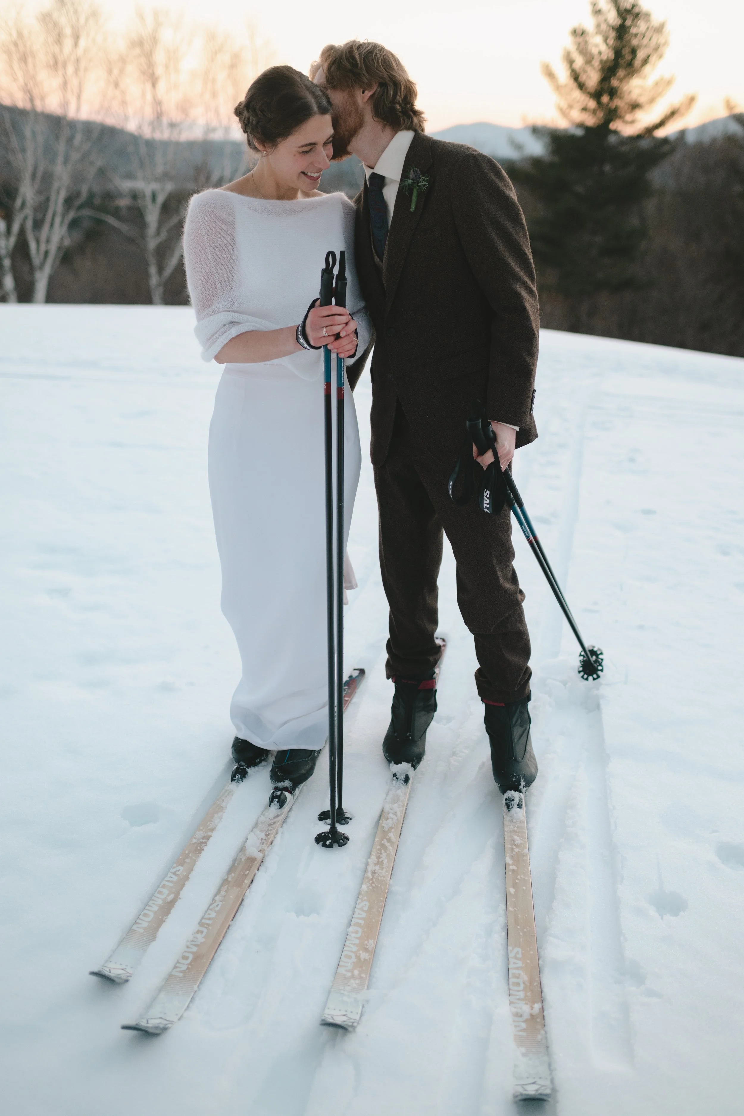 couple cross country skiing after their winter wedding in Vermont  bride and groom skiing in wedding attire Wilburton Inn Manchester VT  cross country ski wedding portraits in snowy Vermont landscape