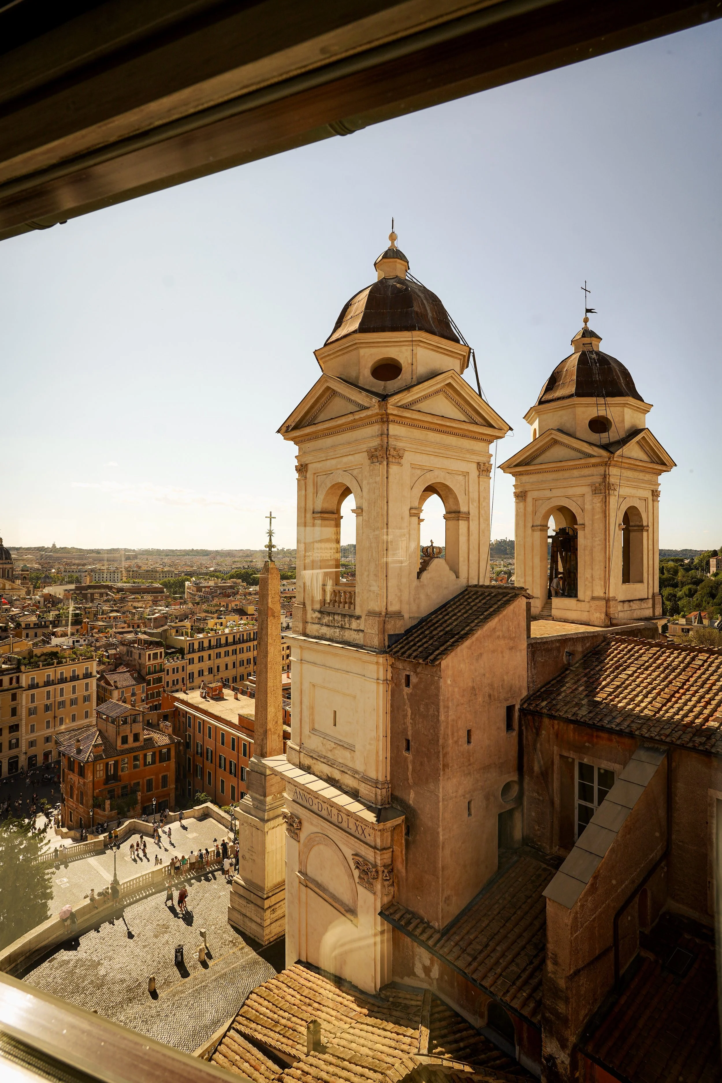 View of historic church with two bell towers and city below, taken from a high vantage point in Rome, Italy.