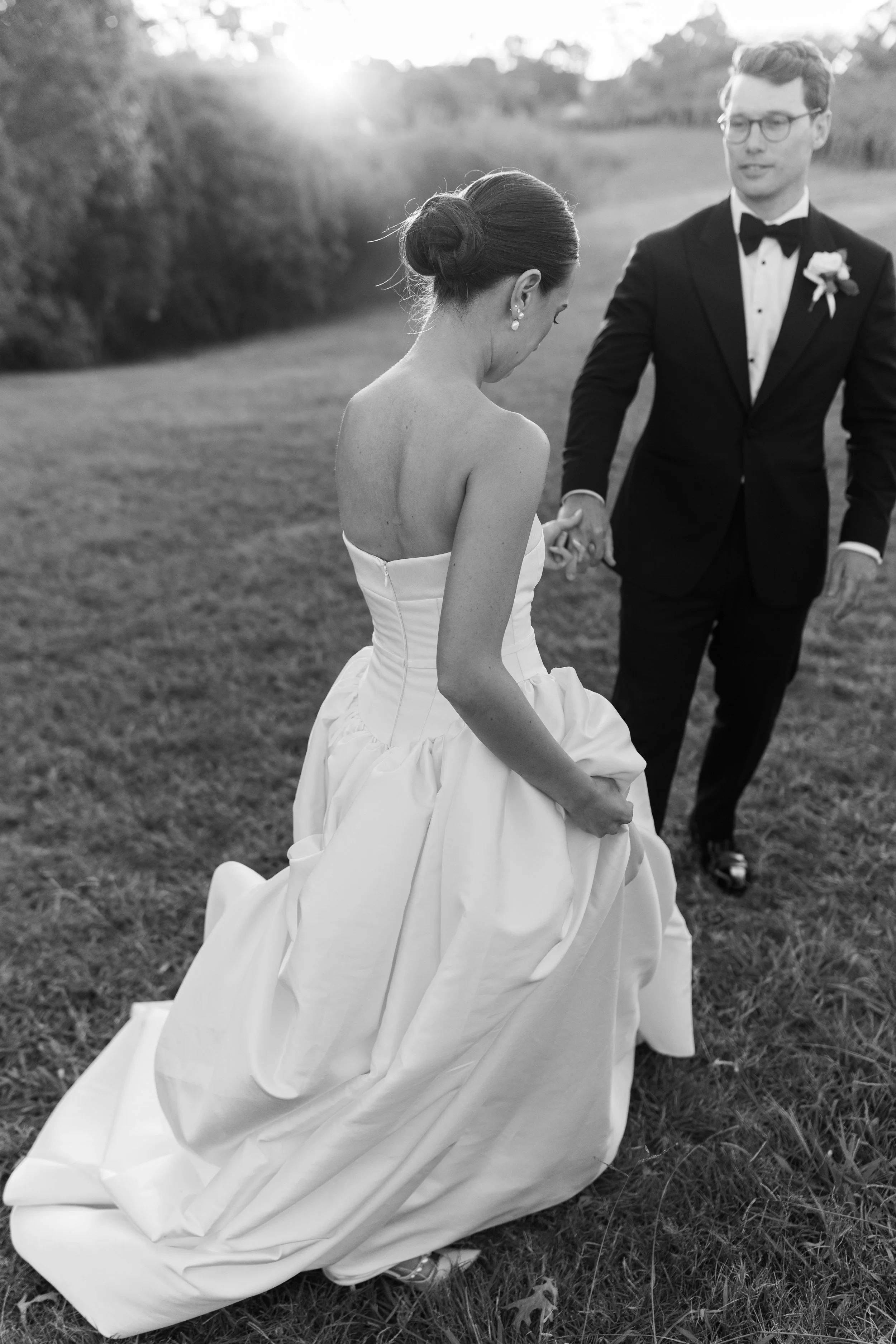 Black and white photo of a Bride and groom in the sunset holding hands and dancing 