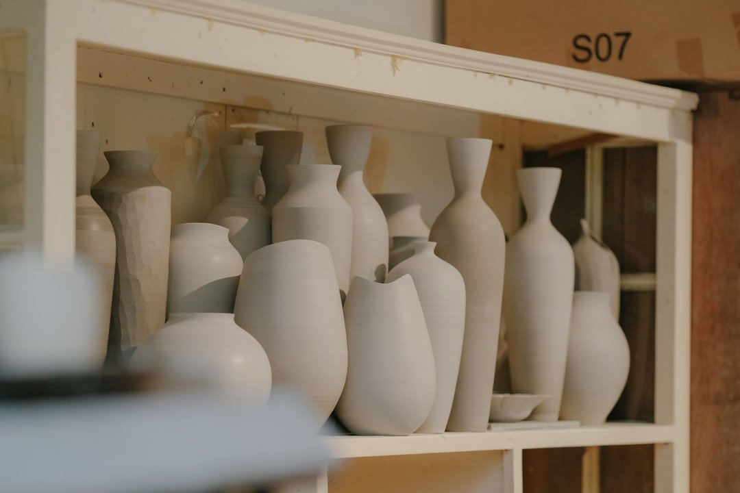 Shelves filled with unfinished ceramic pottery and vases in a pottery studio.